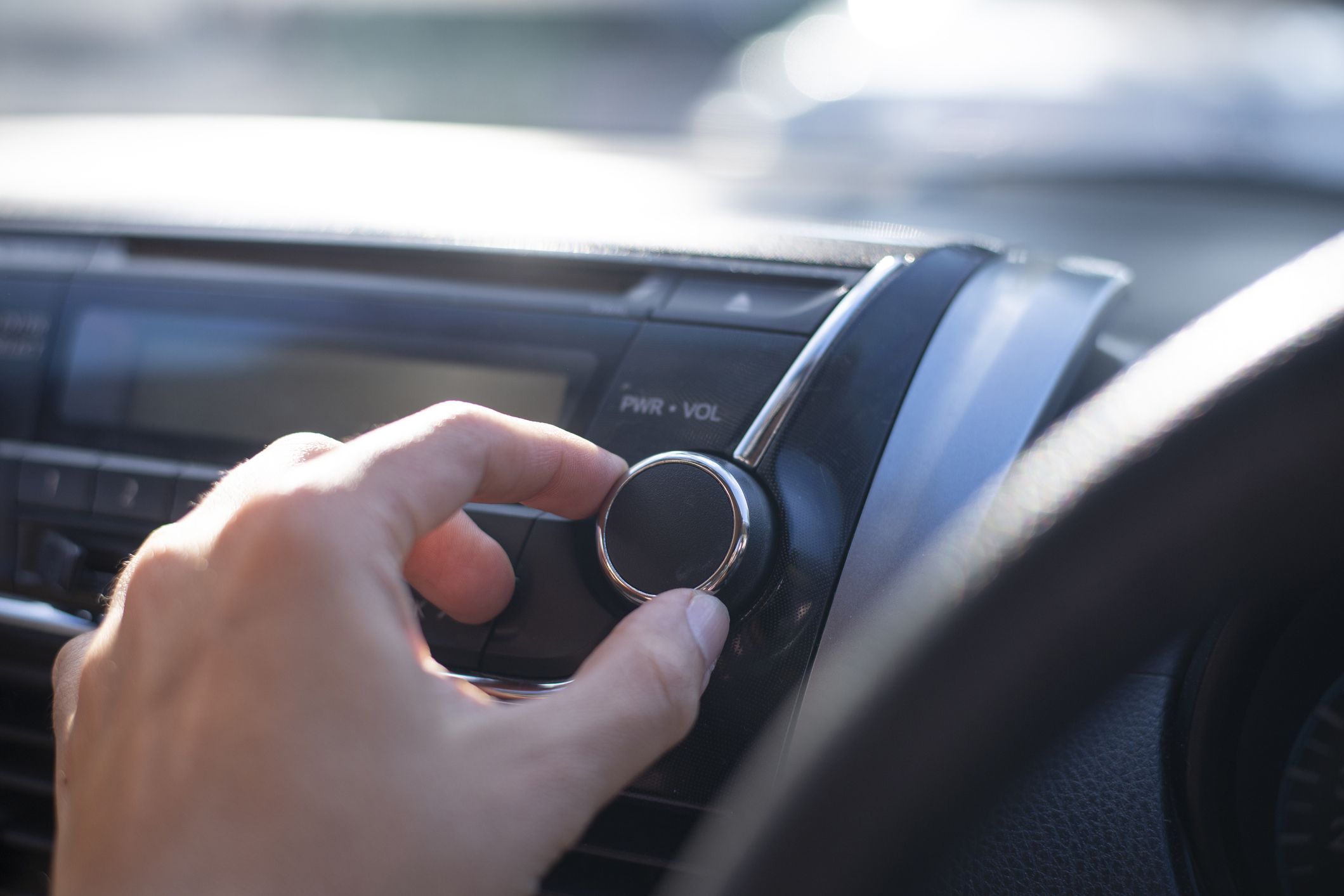 hand adjusting car radio volume