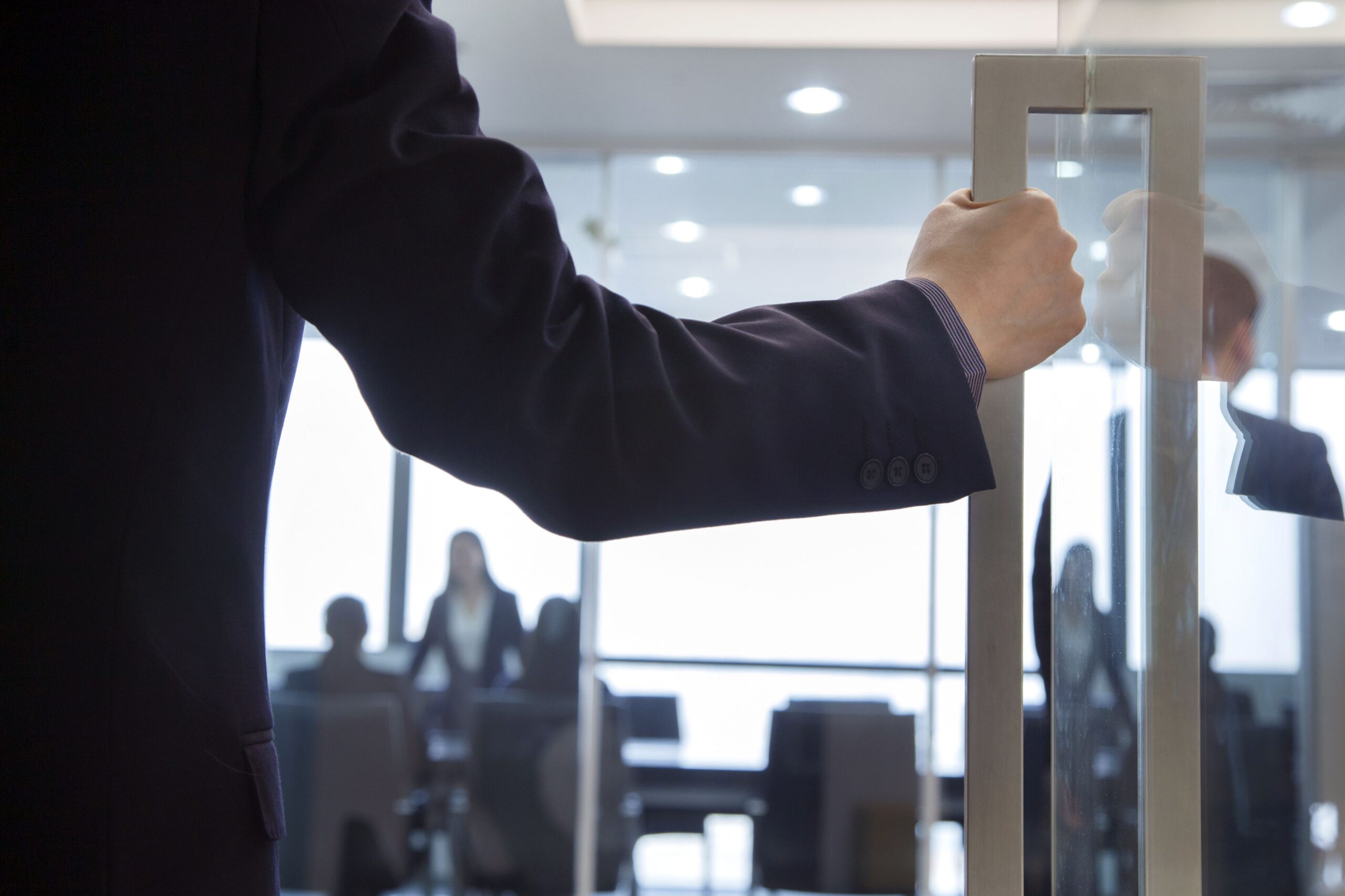 hand pulling door to enter office where meeting is taking place