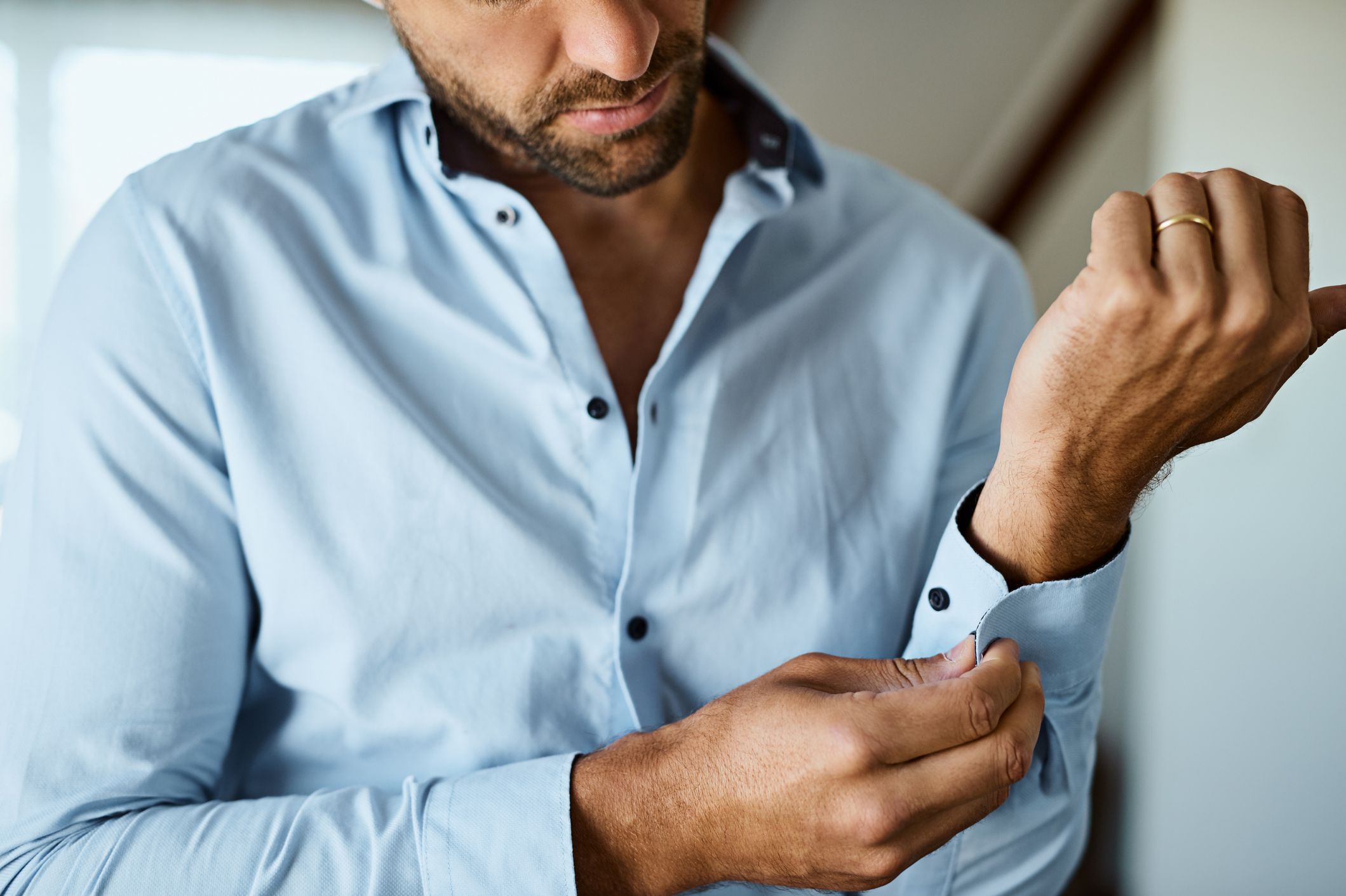 man buttoning shirt cuff