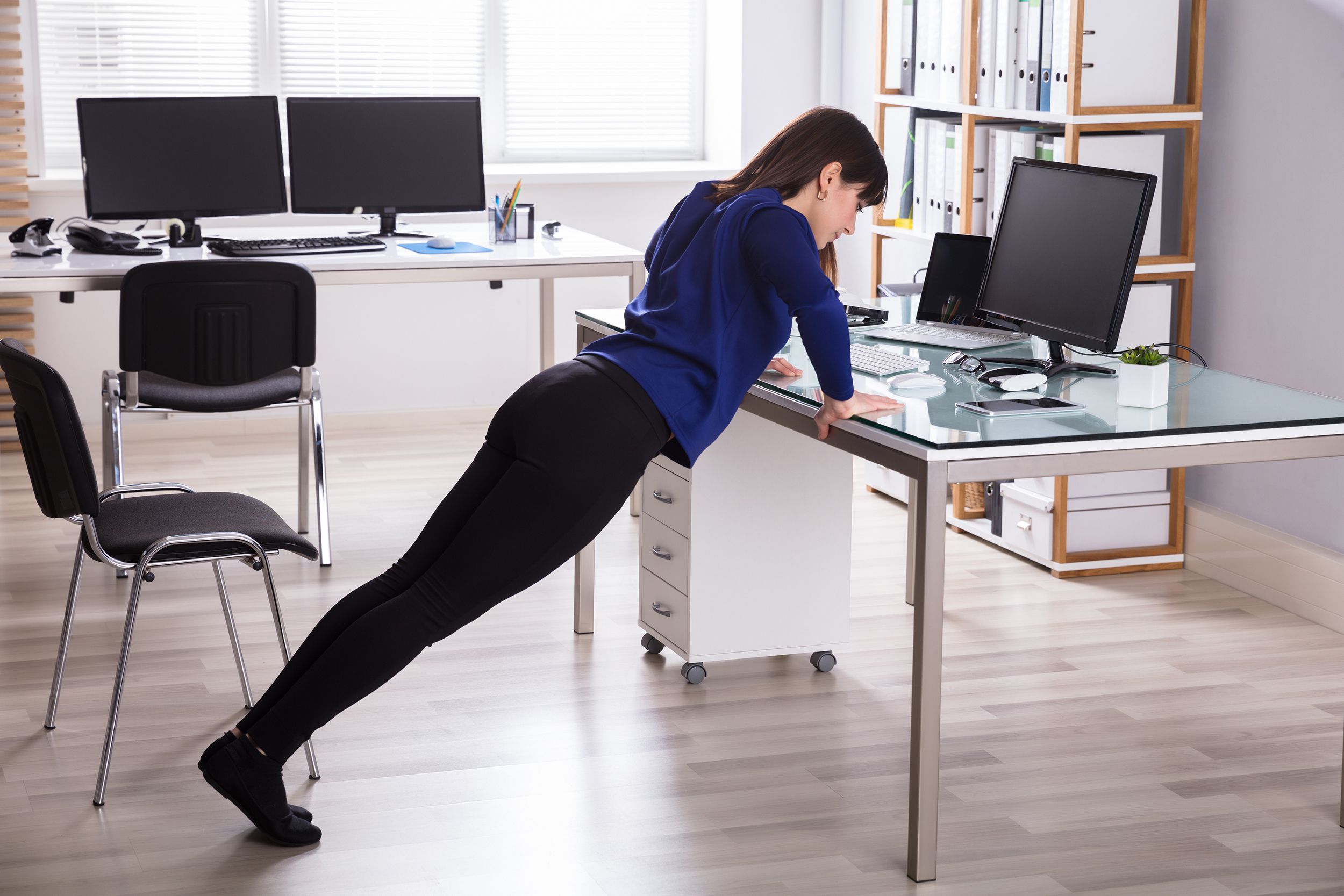 businesswoman doing push up on office desk