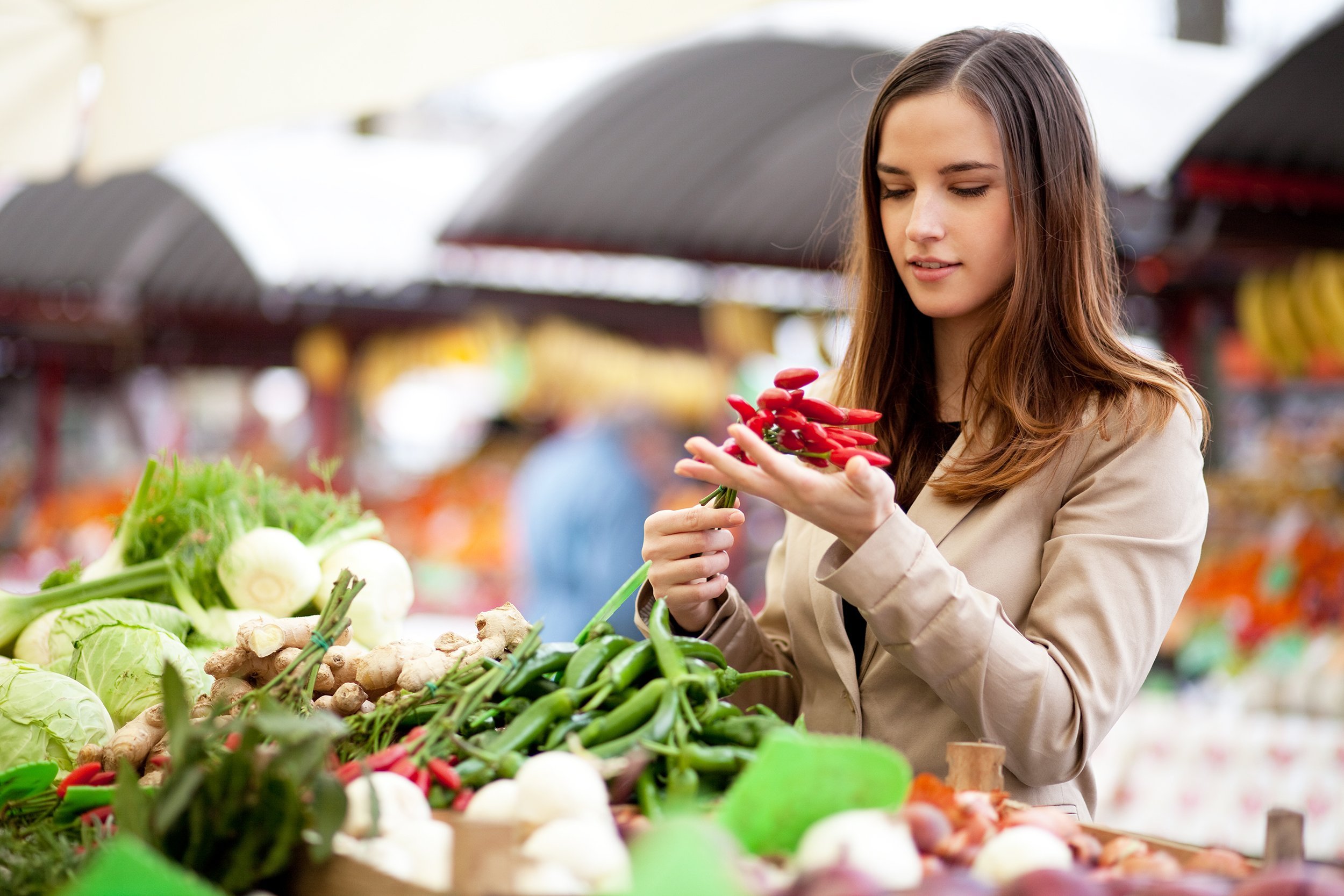 young woman buying red hot chili peppers at the market