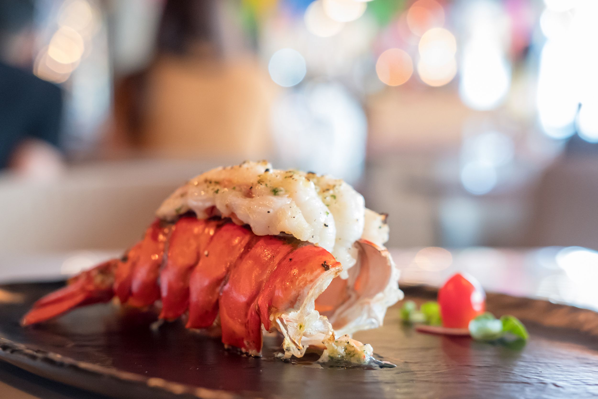grilled lobster tail and vegetables on plate in a restaurant