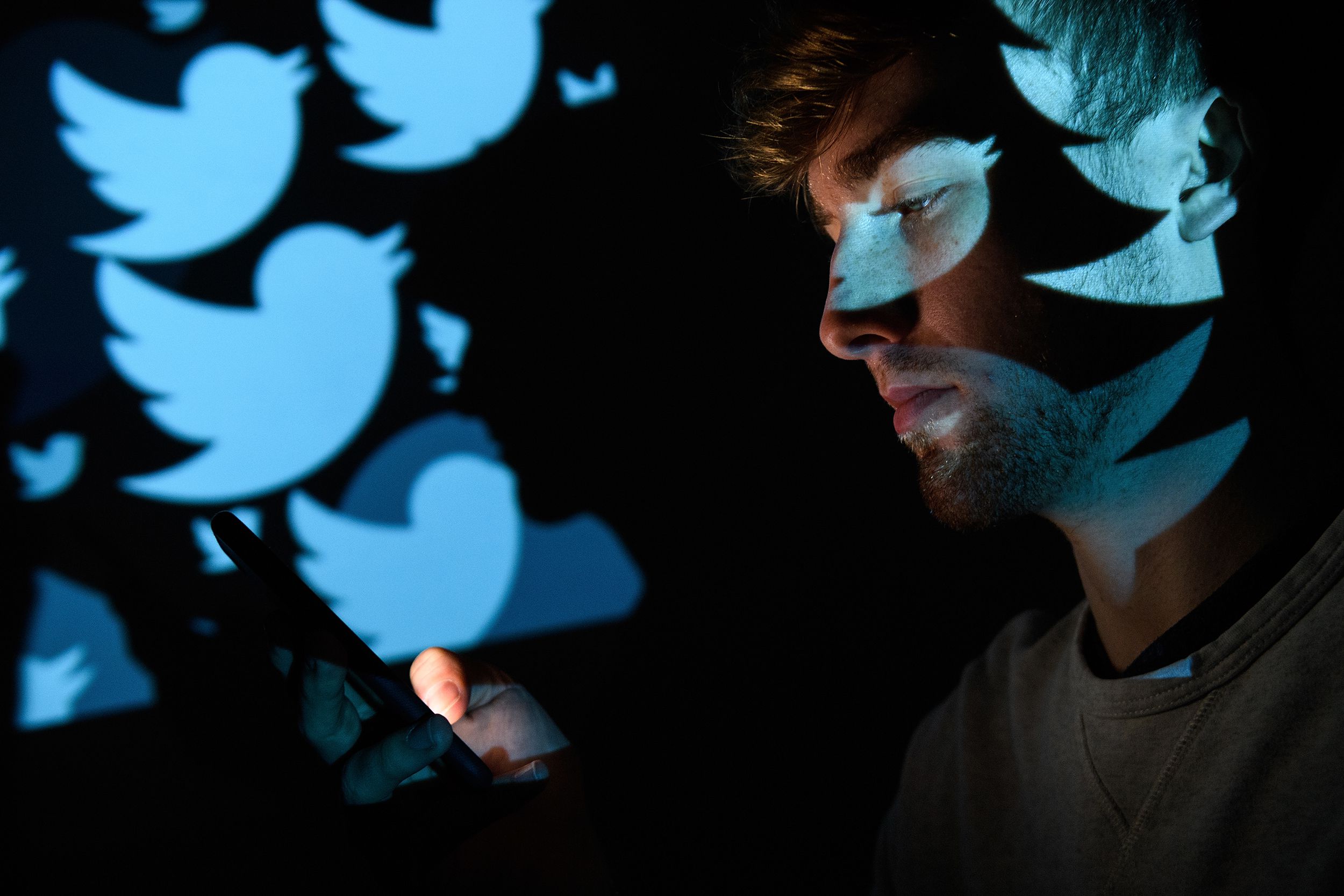 In this photo illustration, the logo for the Twitter social media network is projected onto a man on August 09, 2017 in London, England.