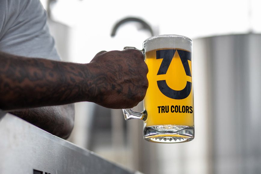 man holding glass of TRU Colors beer in TRU Colors brewery