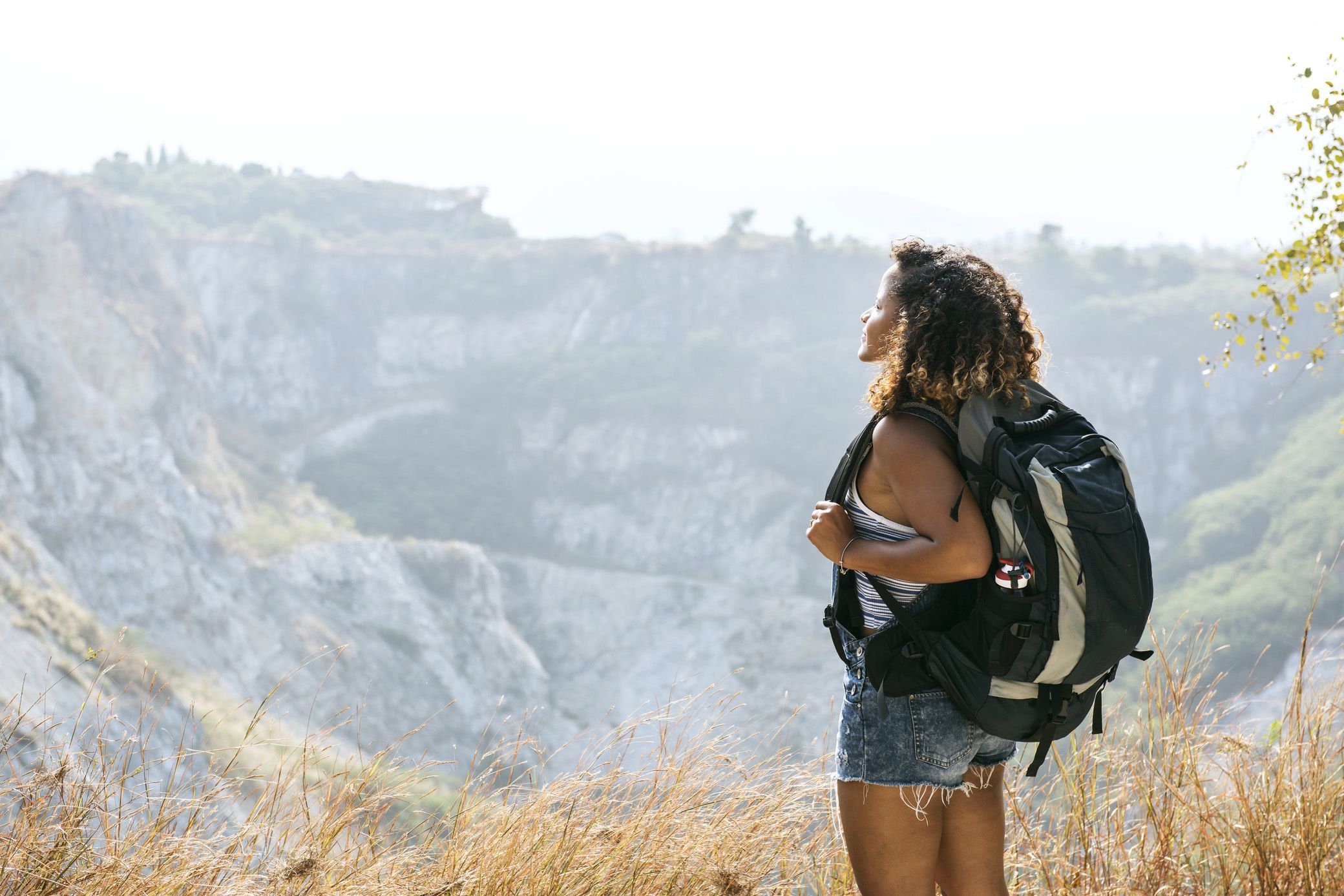 woman traveler with backpack looking out at view from mountain
