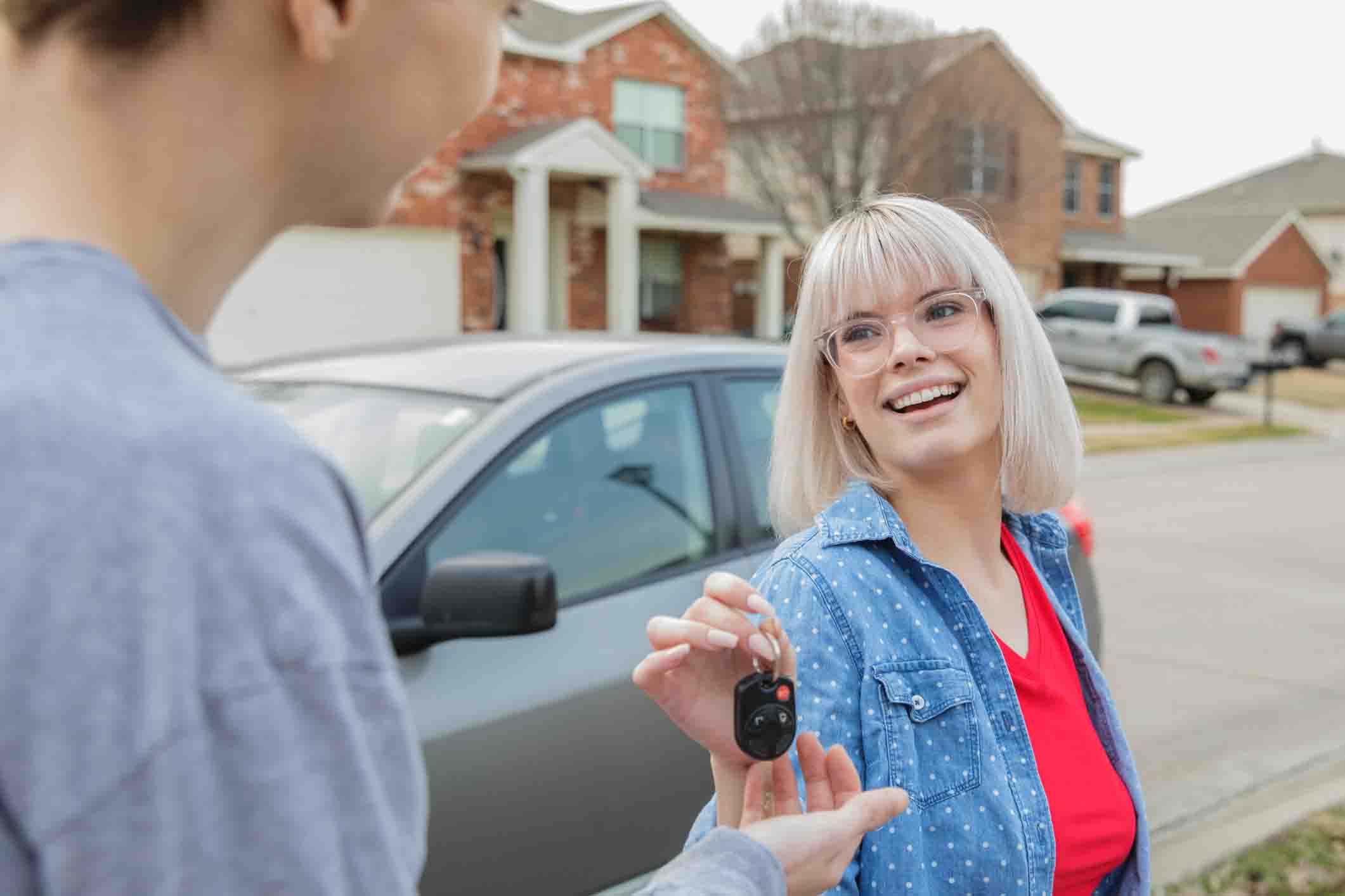 young woman giving car keys to young person