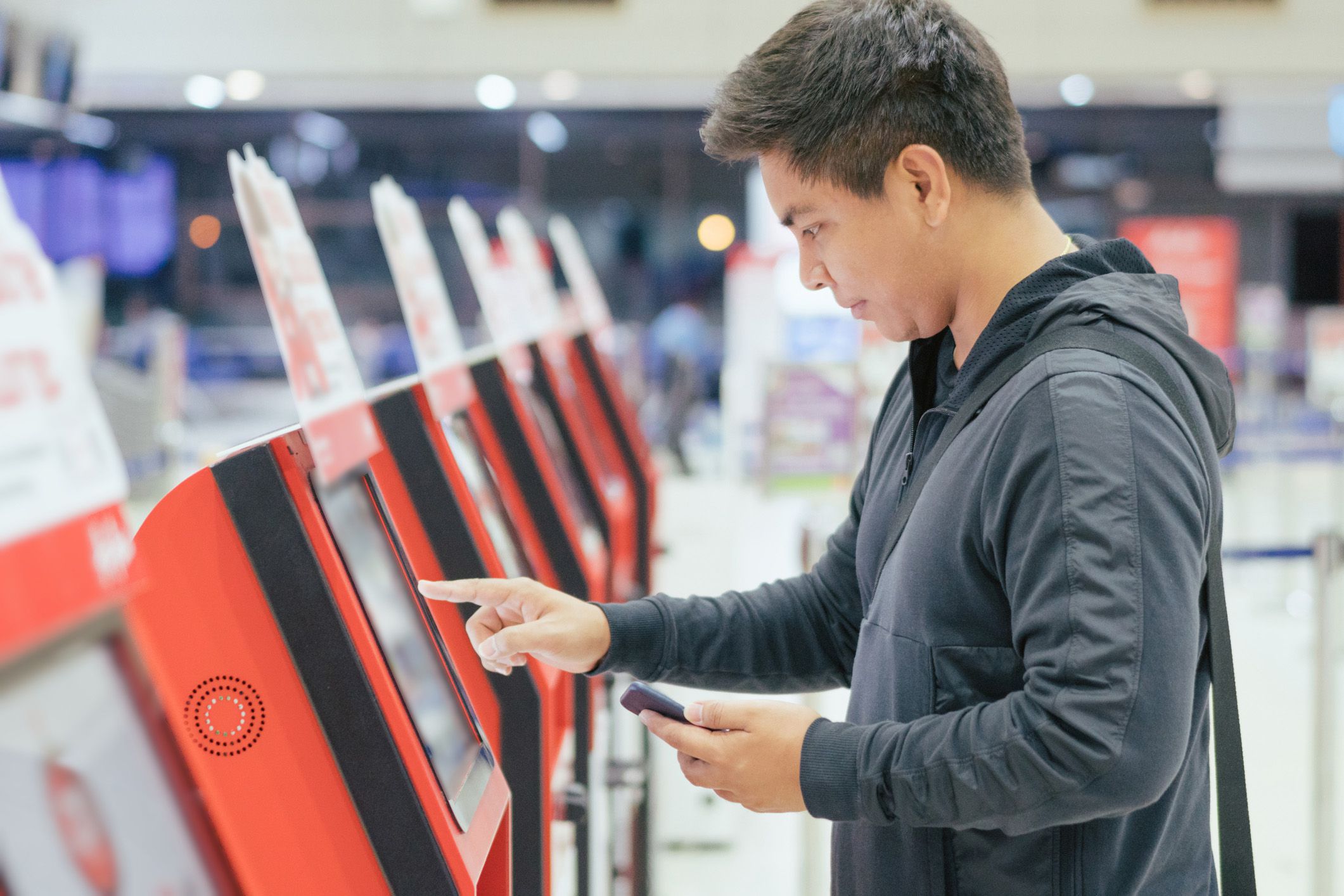 young passenger at the self-service check-in machine in departure hall at airport