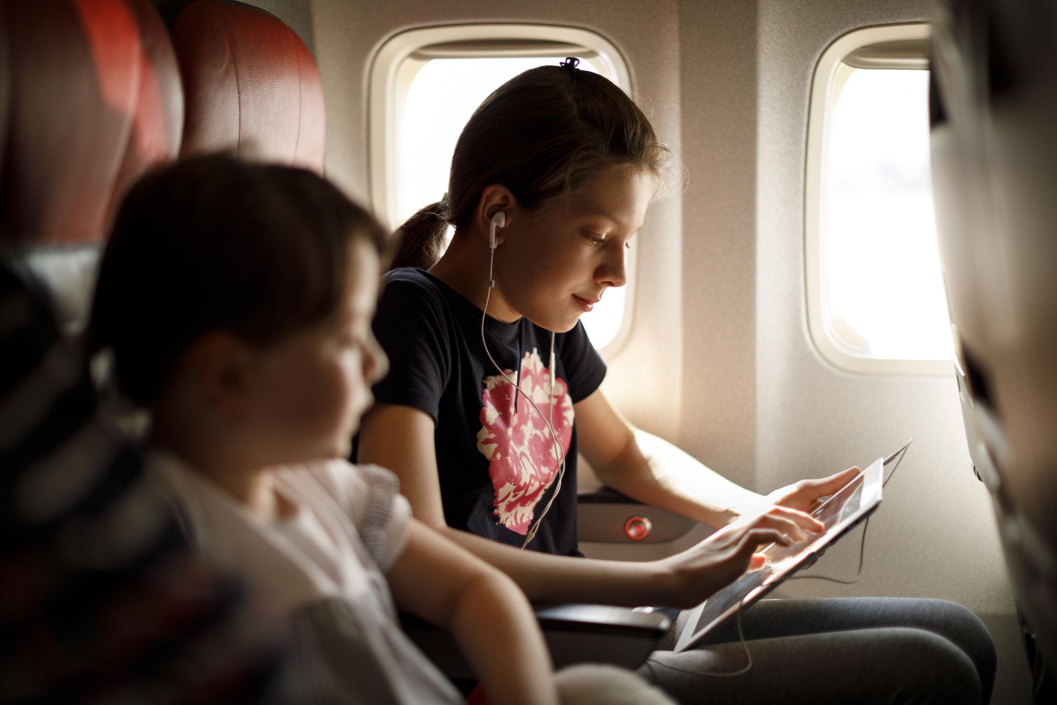two girls on plane looking at tablet