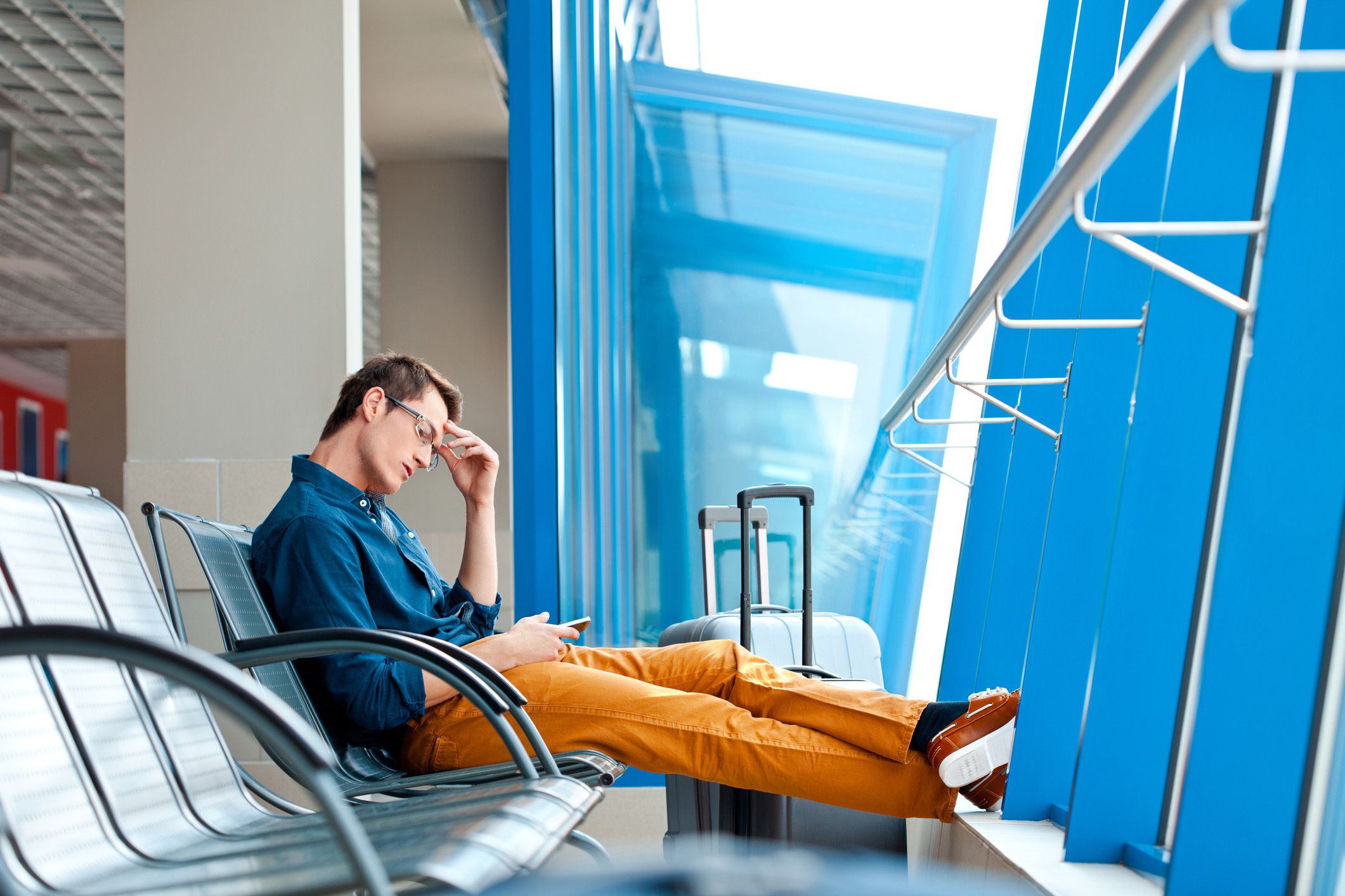 man frustrated looking at phone at airport gate
