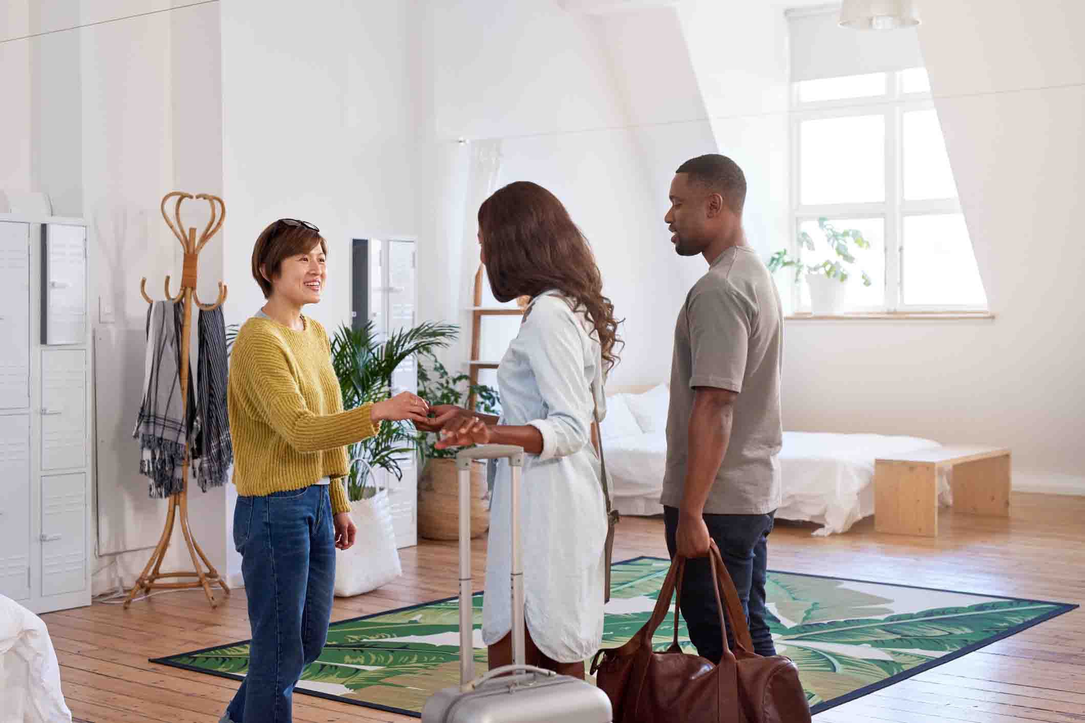 woman giving keys to guests in home