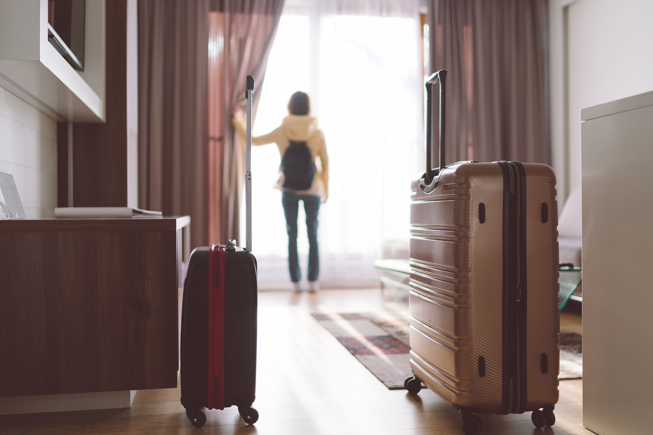 tourist woman opening blinds in hotel room