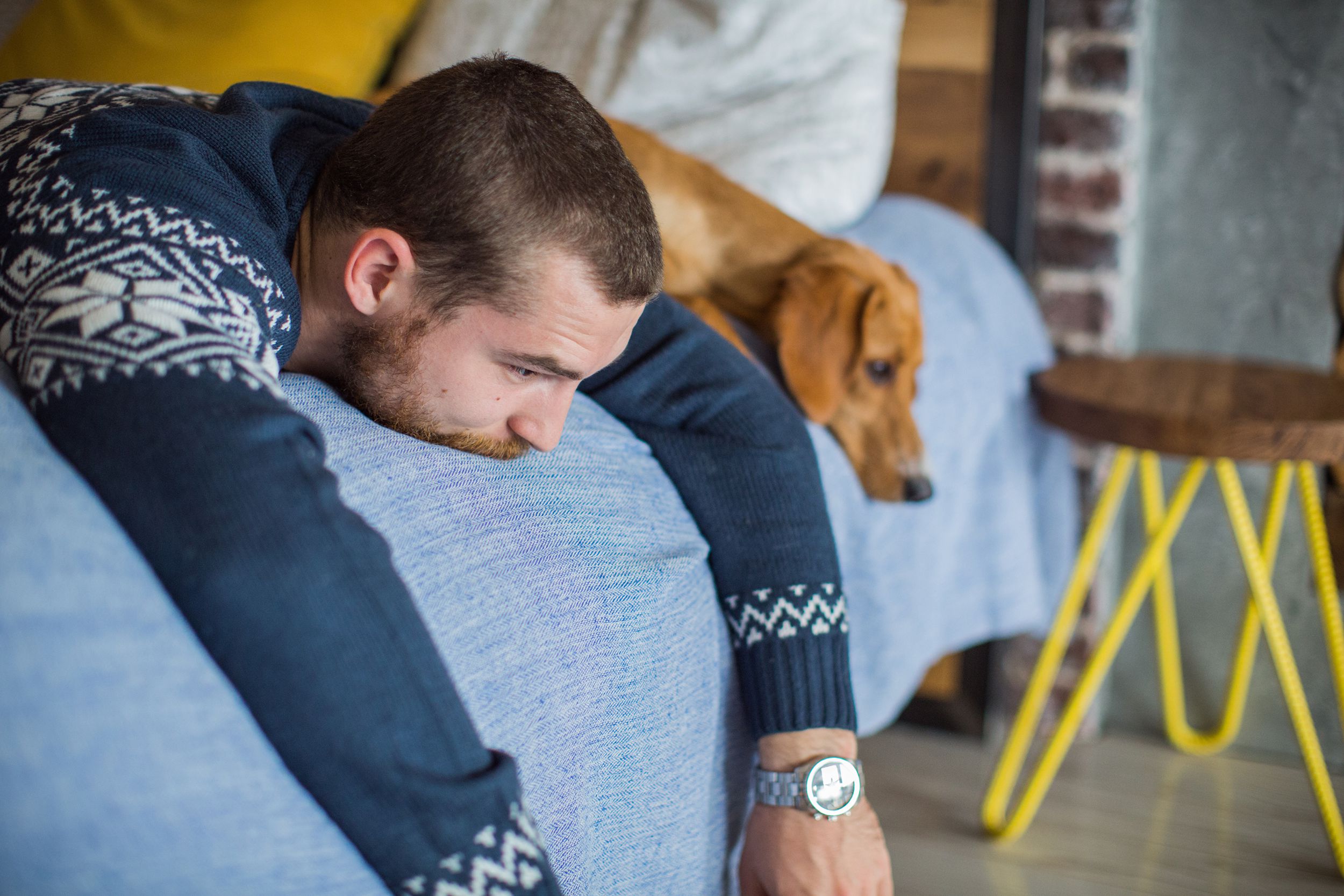 depressed man laying on bed with dog at home