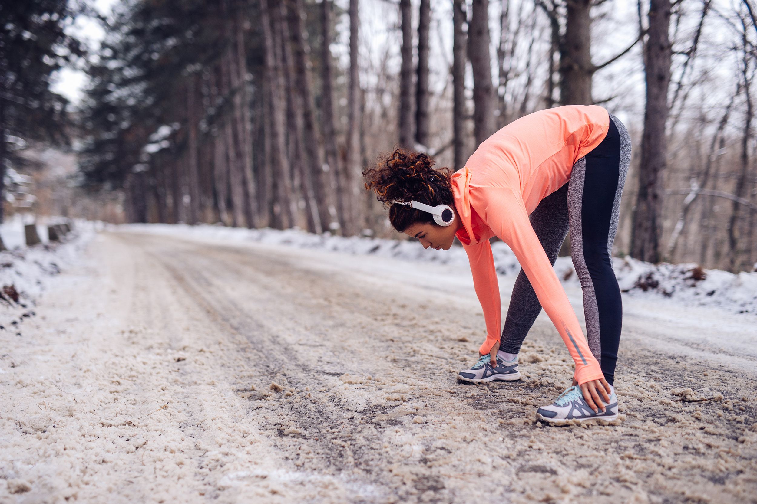 woman stretching her muscles before a jog on snowy road