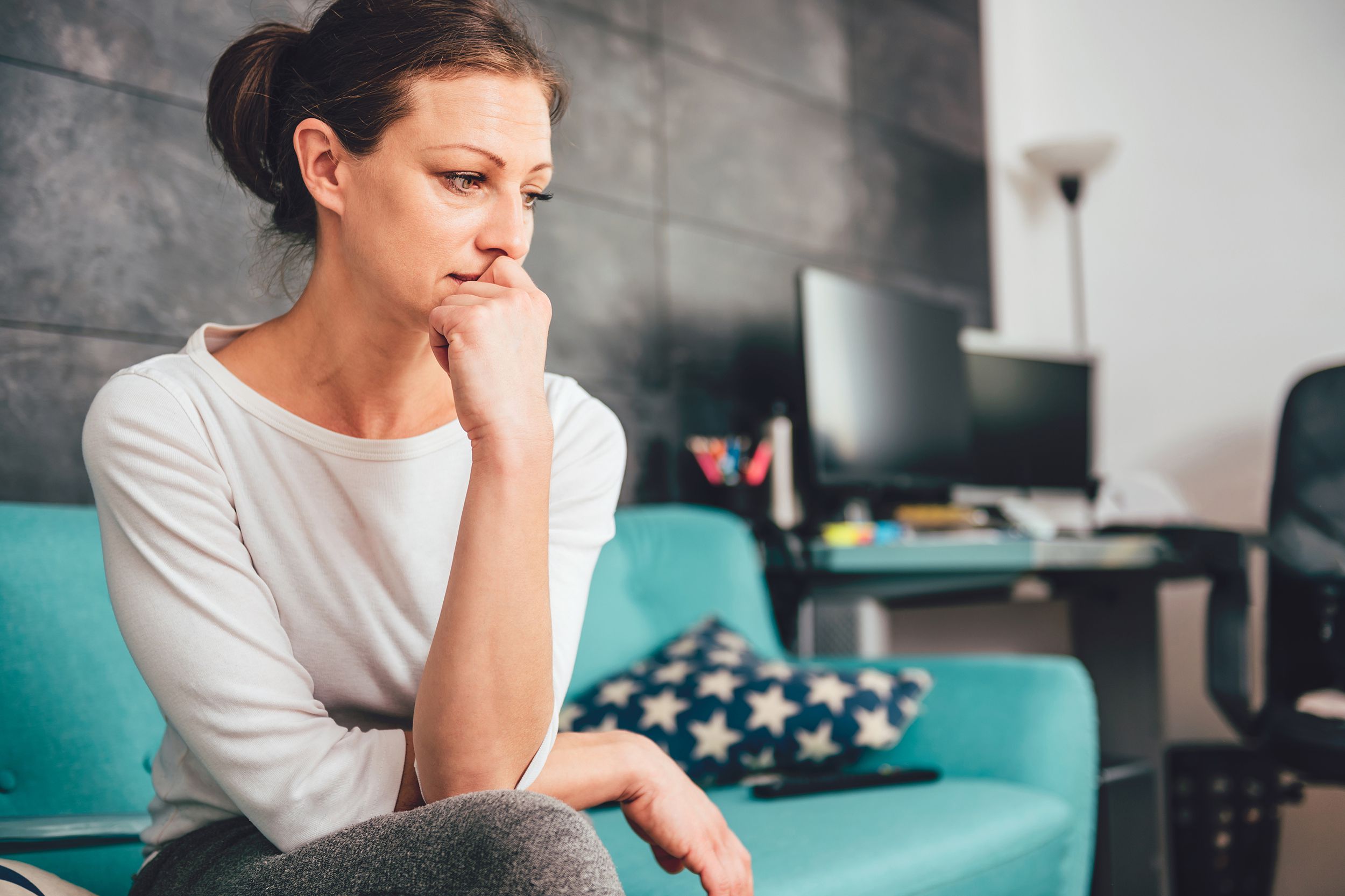 pensive woman sitting on couch in her home office