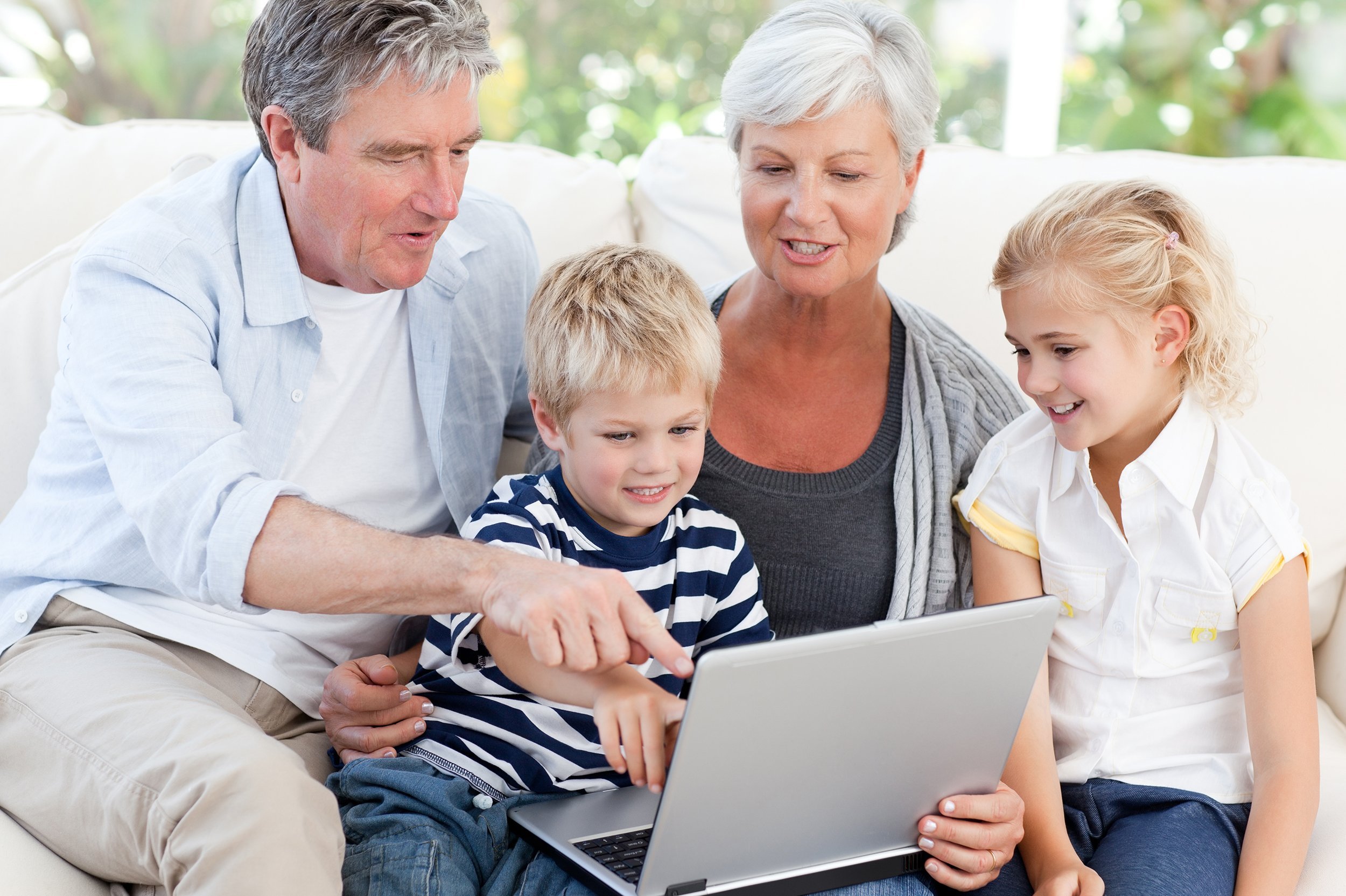 grandparents and grandchildren looking at their laptop