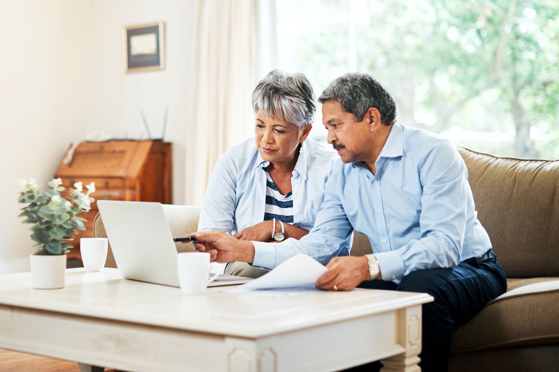 elderly couple looking at papers and computer with serious expressions
