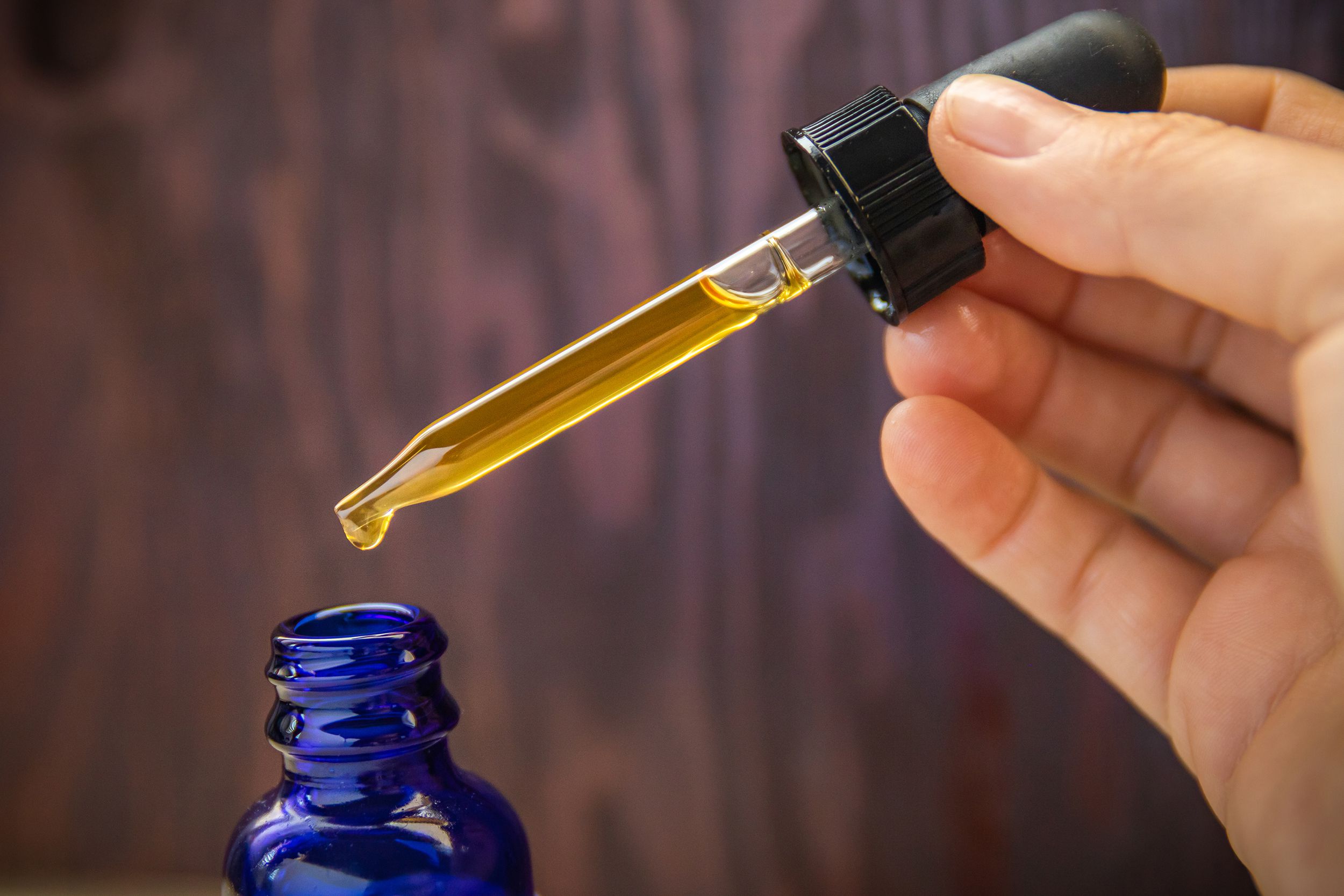 CBD oil extract in dropper & blue bottle up close