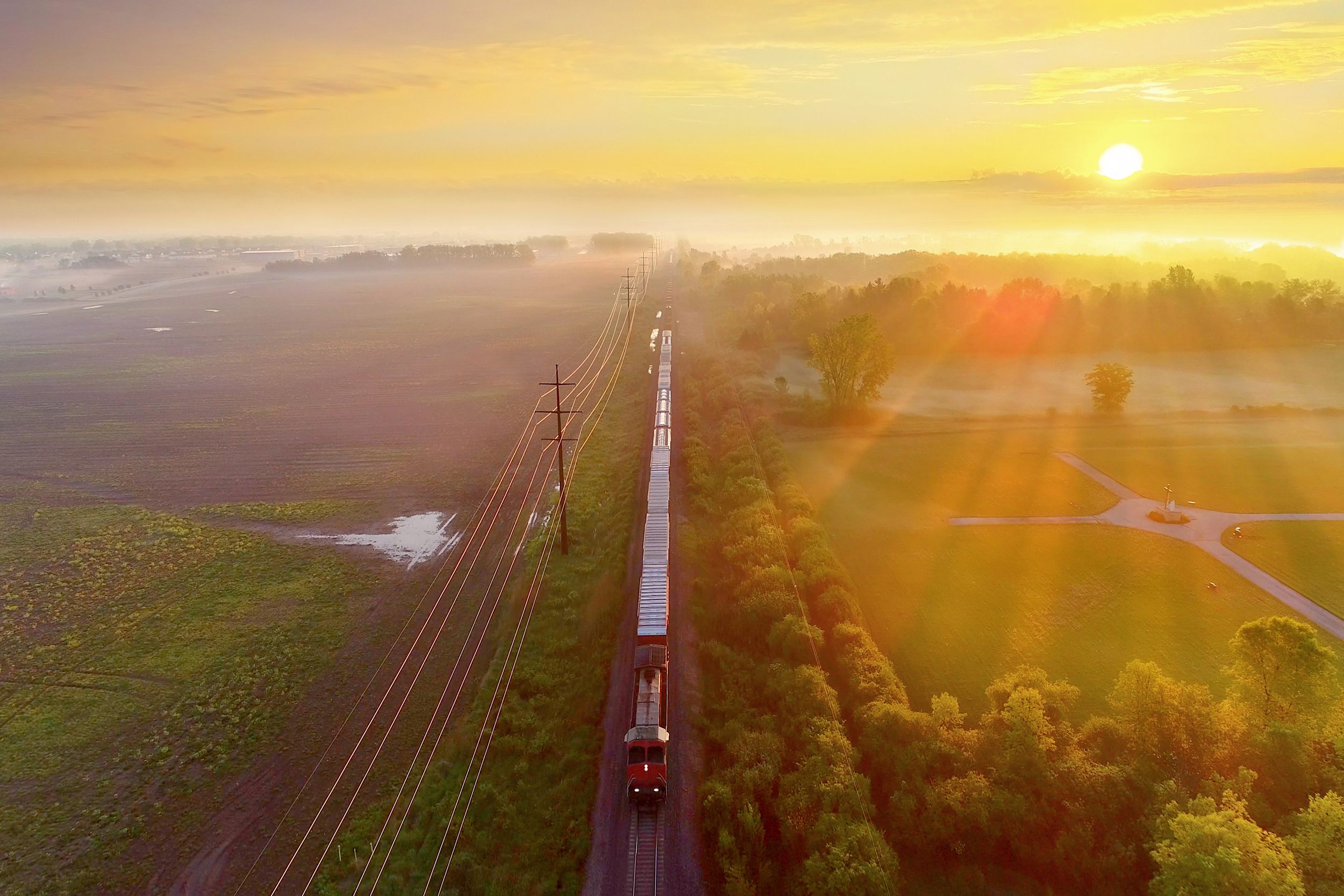 train rolls through foggy rural landscape at sunrise, Wisconsin