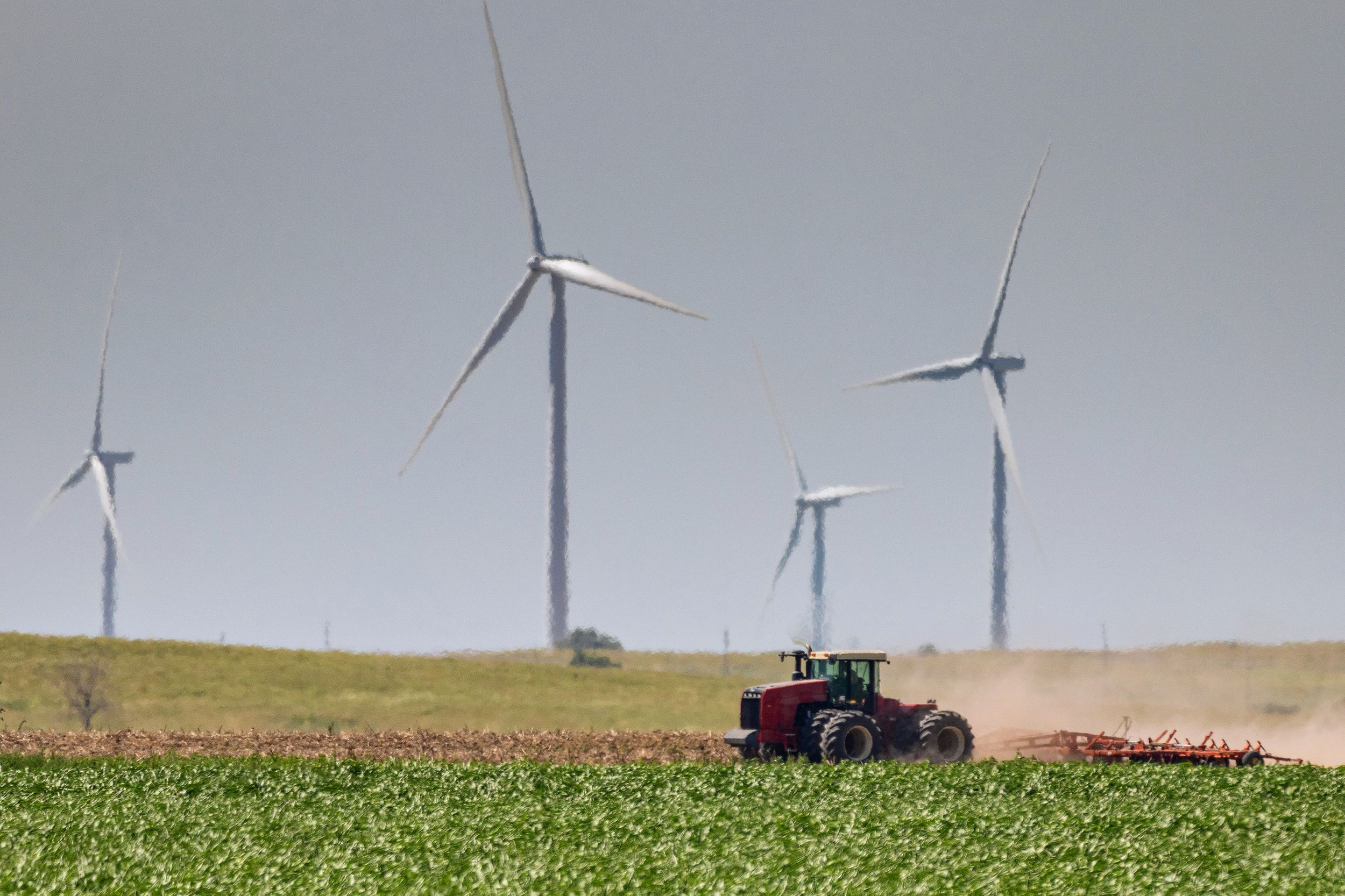 farmer discing his field as giant wind turbines, Kansas