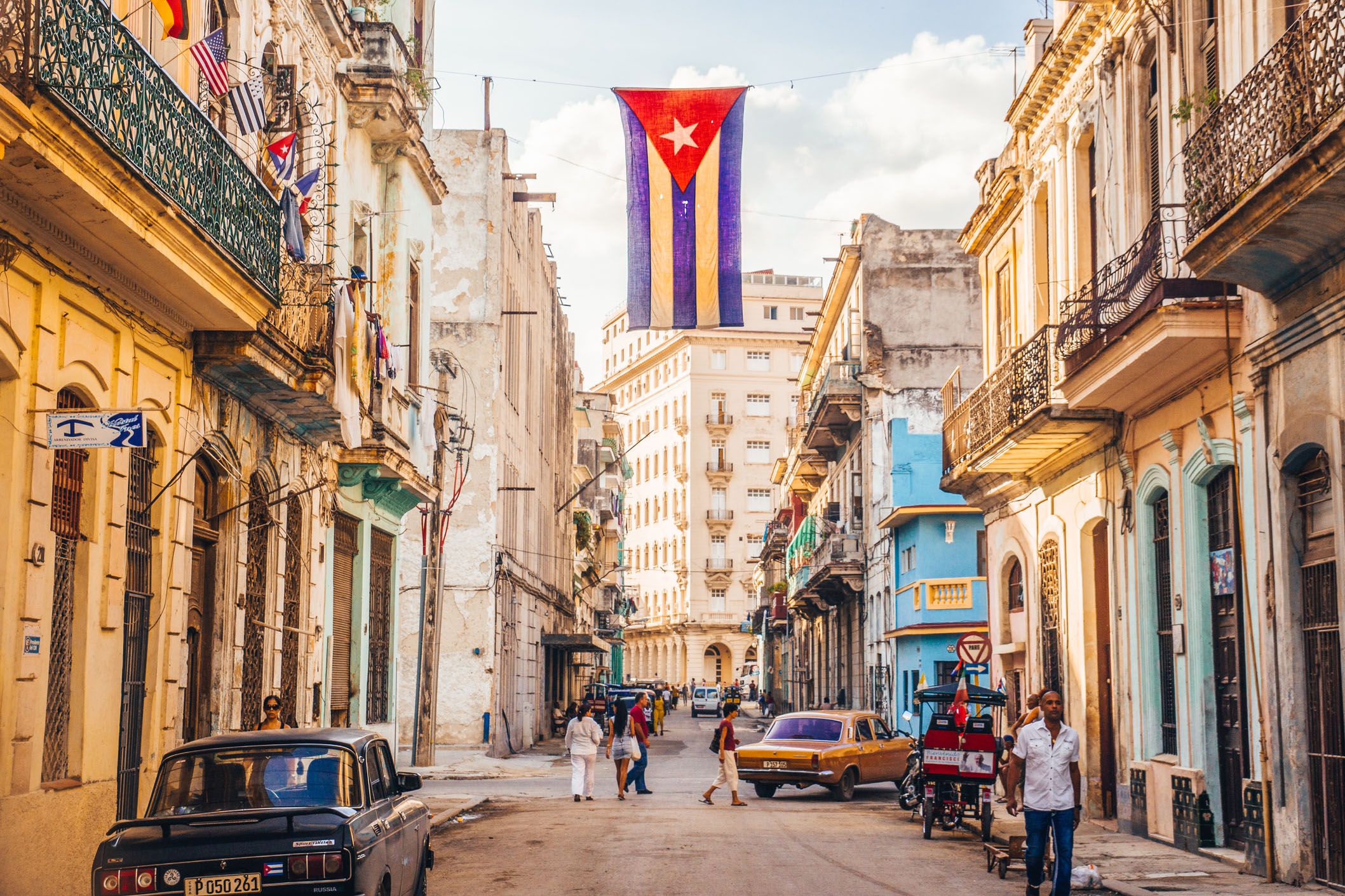 a cuban flag with holes waves over a street in central havana