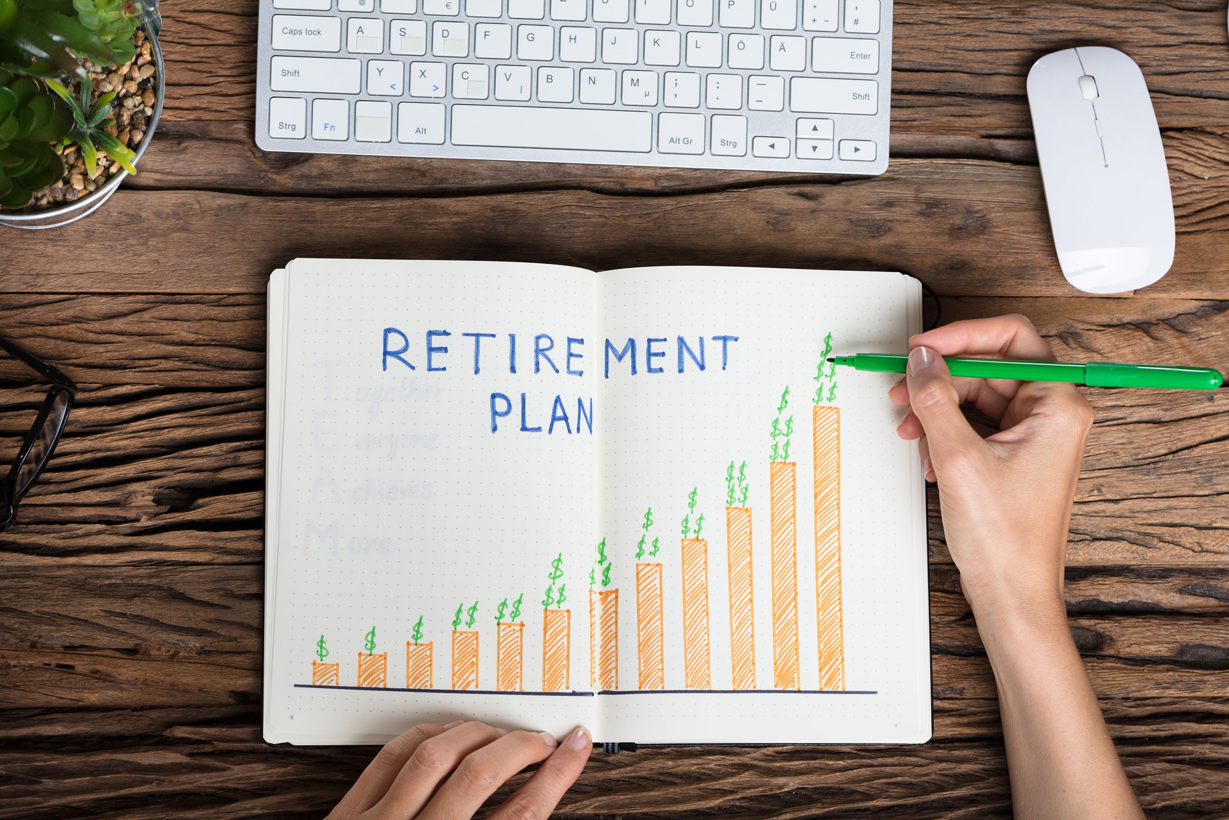 elevated view of a human hand drawing retirement plan growth concept on notebook