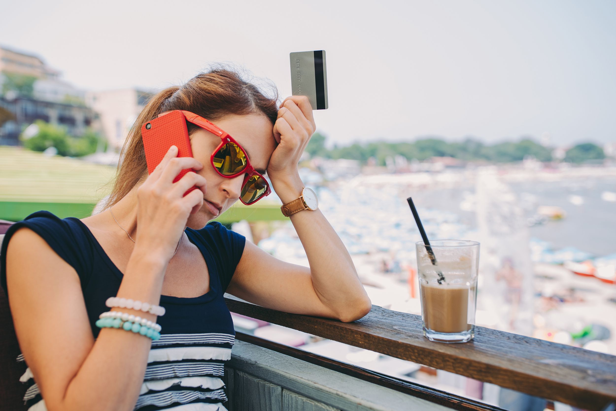frustrated woman on cell with credit card at outdoor restaurant