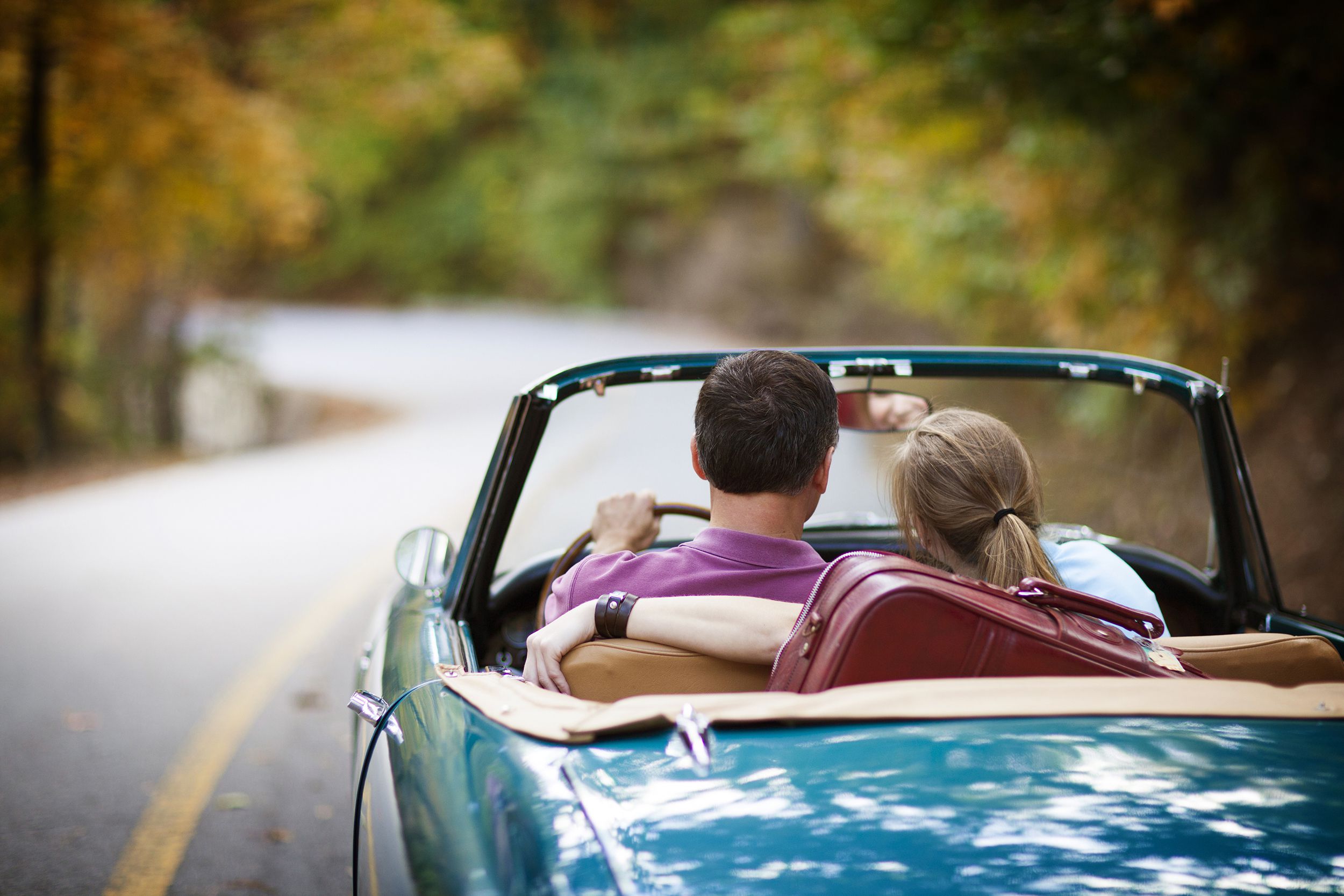 couple driving in a convertible during fall