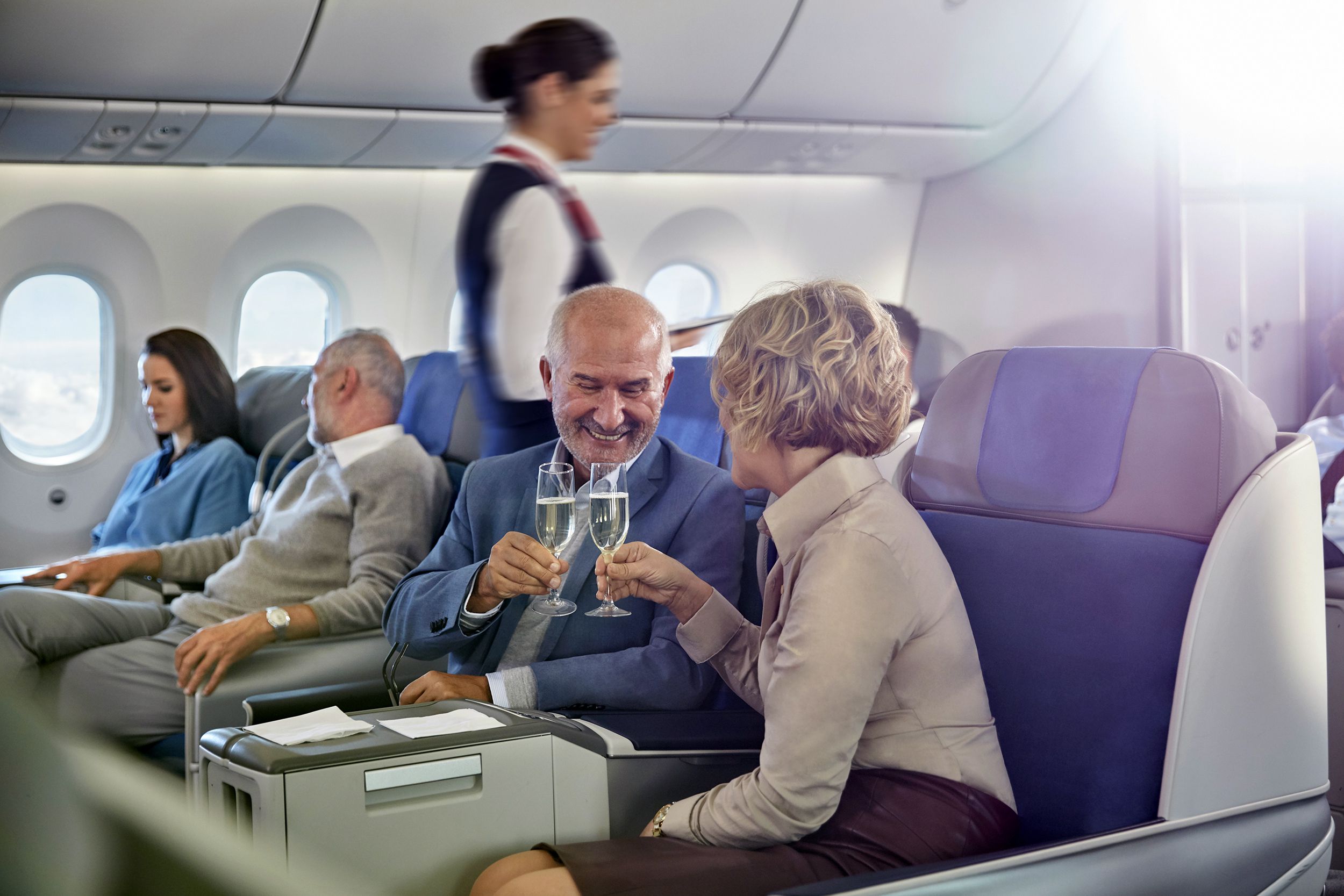 mature couple toasting champagne glasses in first class on airplane