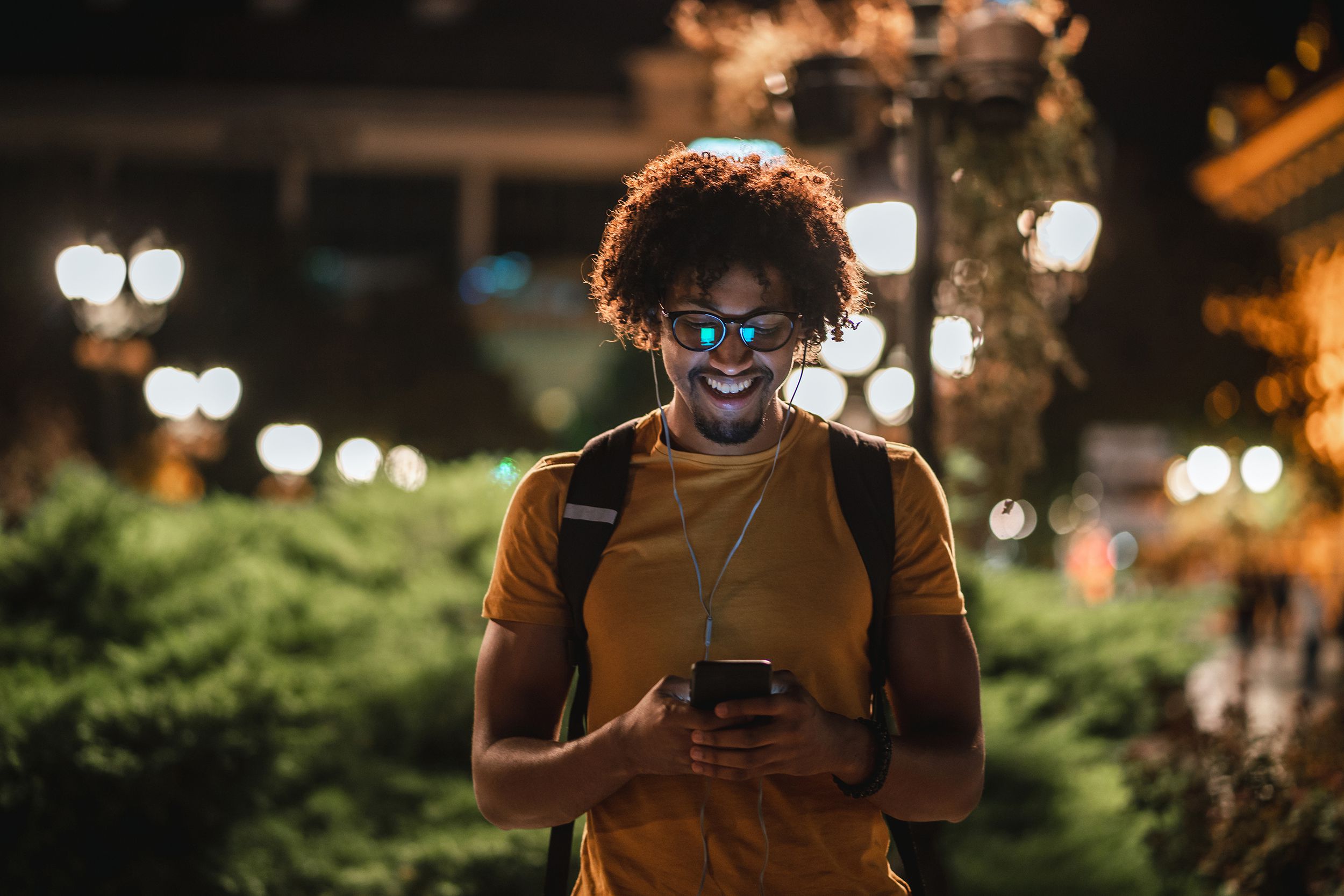 smiling young man texting on phone outside