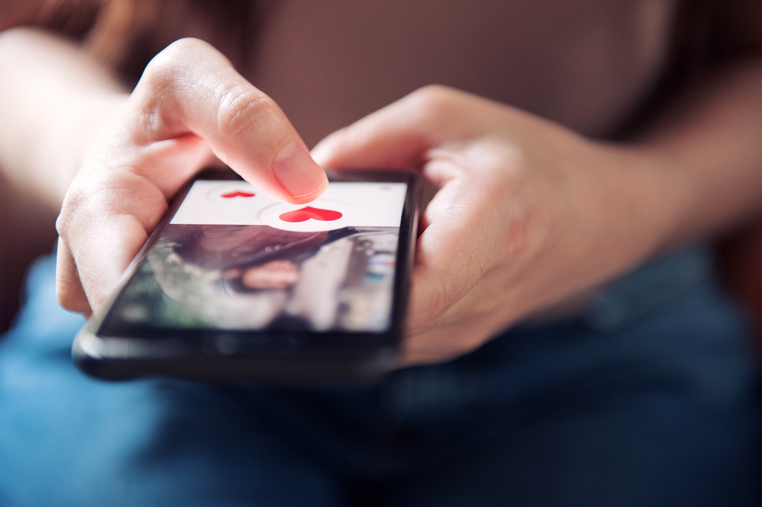 Woman using a heart emoji on her phone