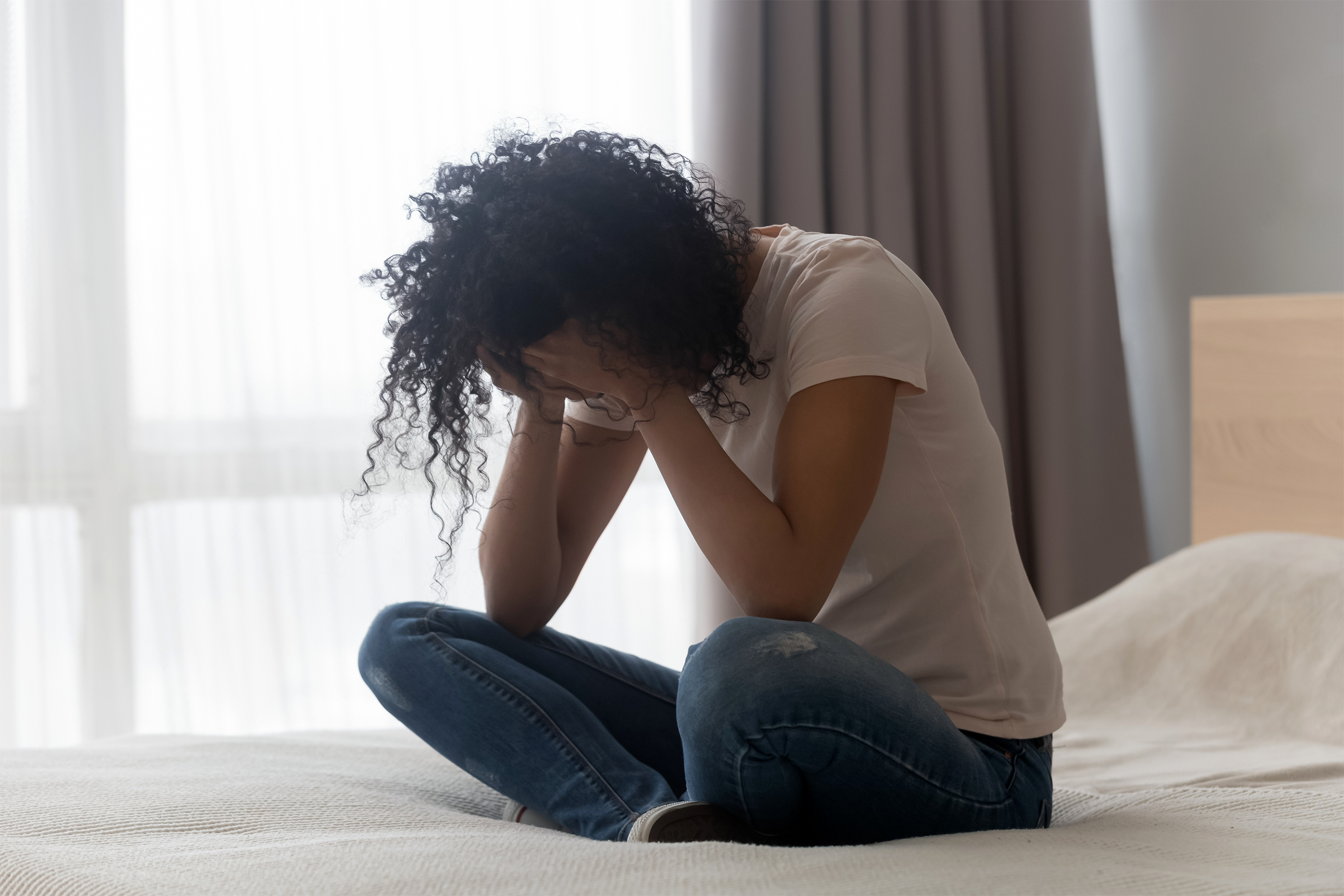 Depressed woman sitting on bed