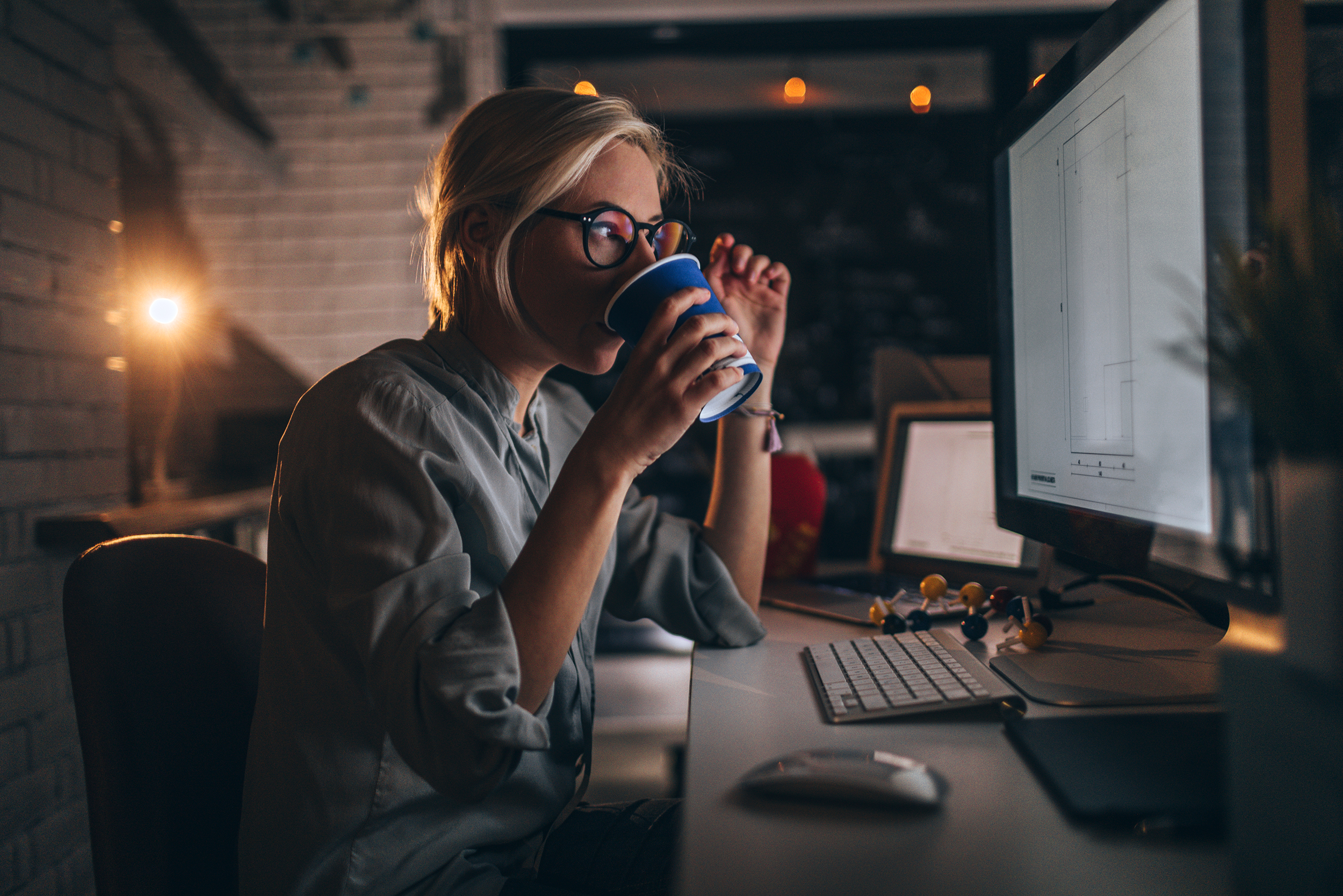 Woman drinking coffee late at night while working on the computer