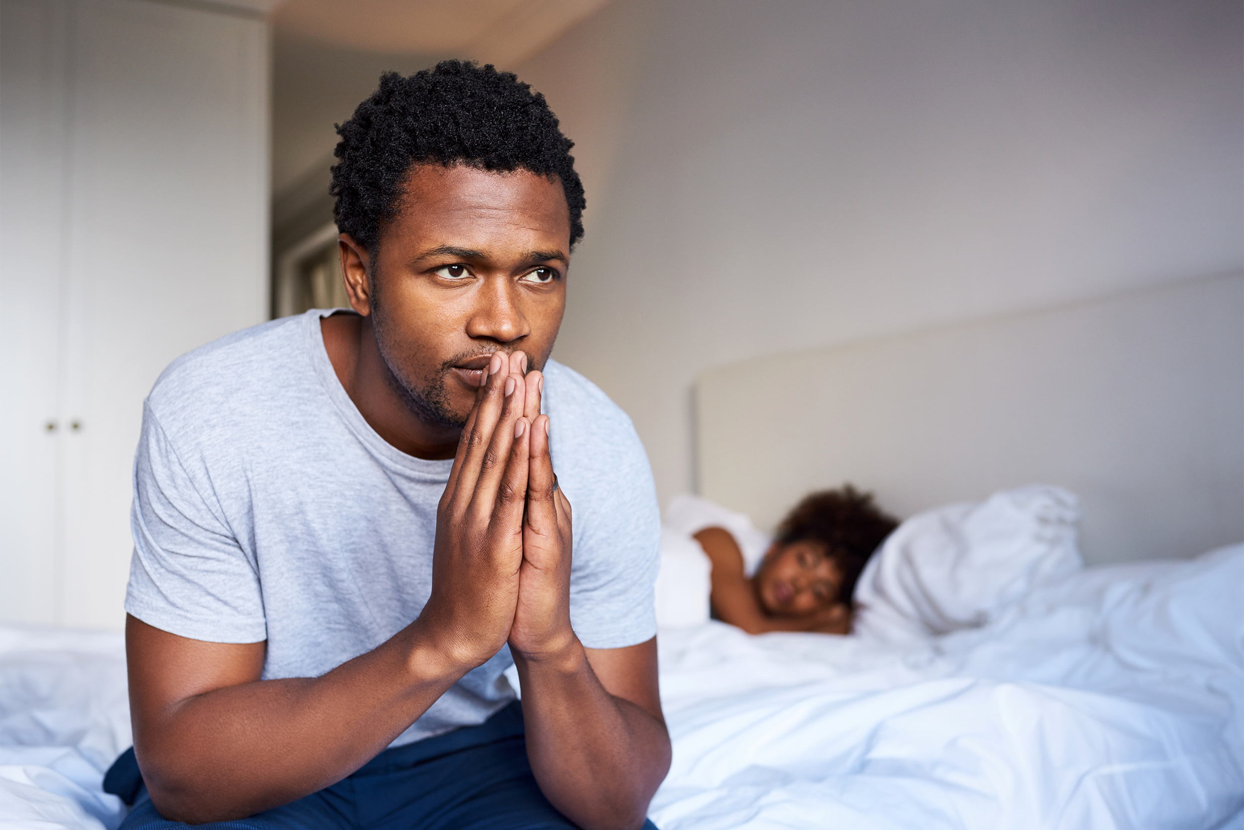 Unsure man sitting on the edge of his bed