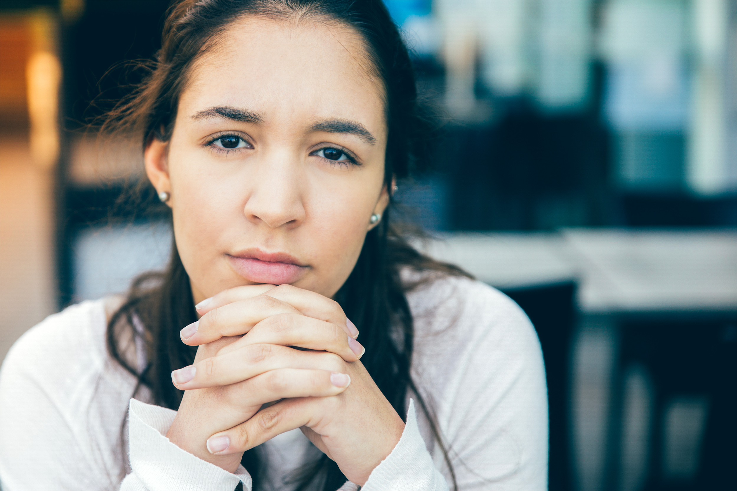 Woman sitting with stern face and hands folded