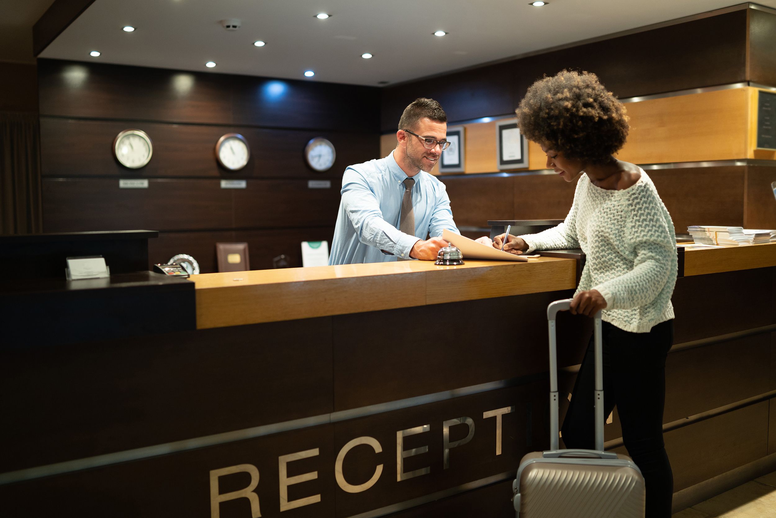 traveler woman signing document at hotel reception desk