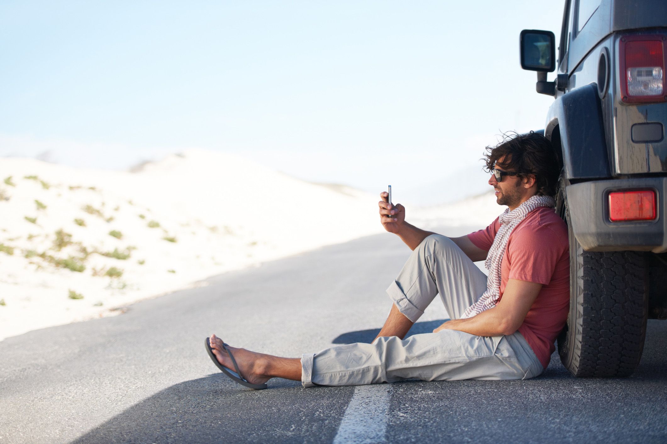 man on road looking at phone, frustrated