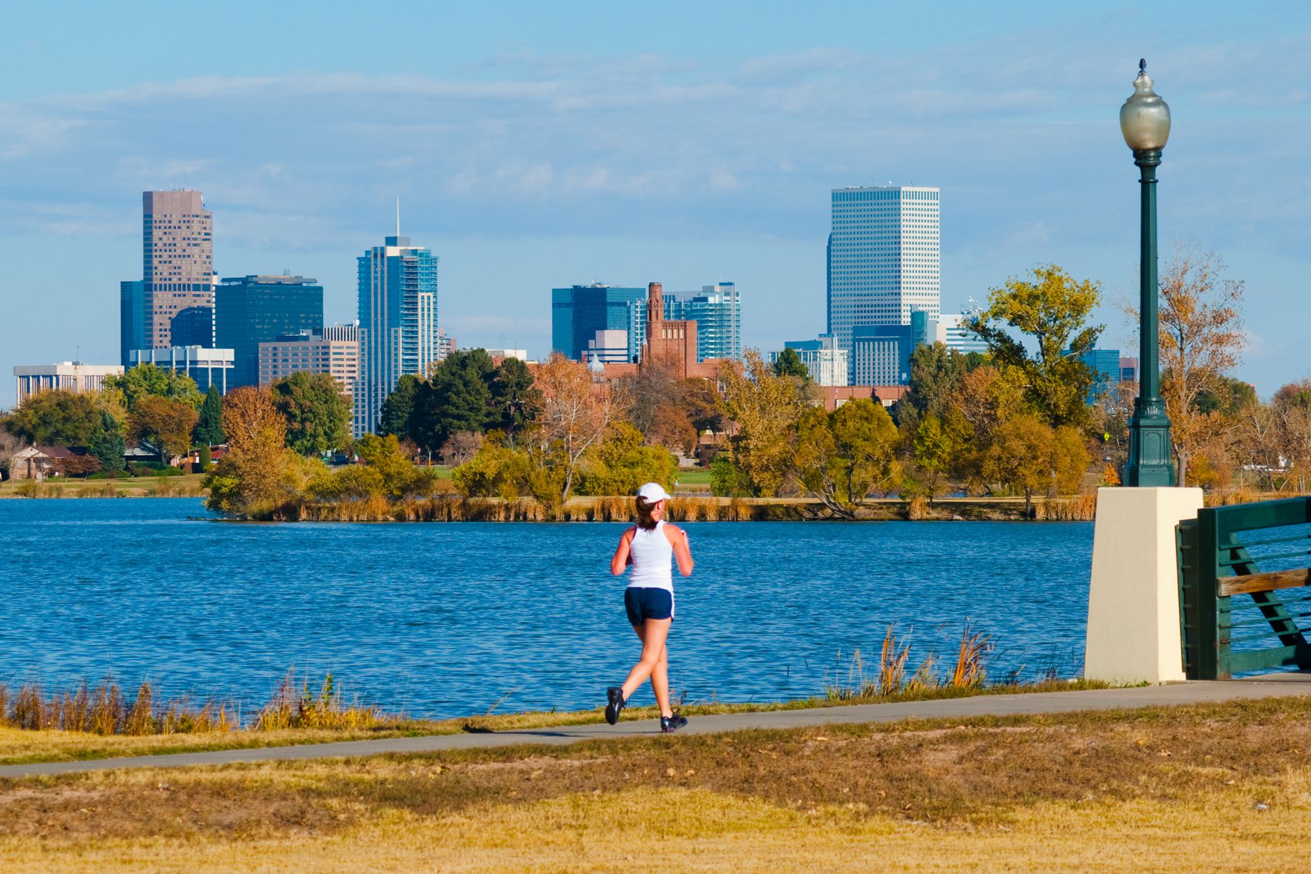 woman jogging with Denver skyline and lake in background