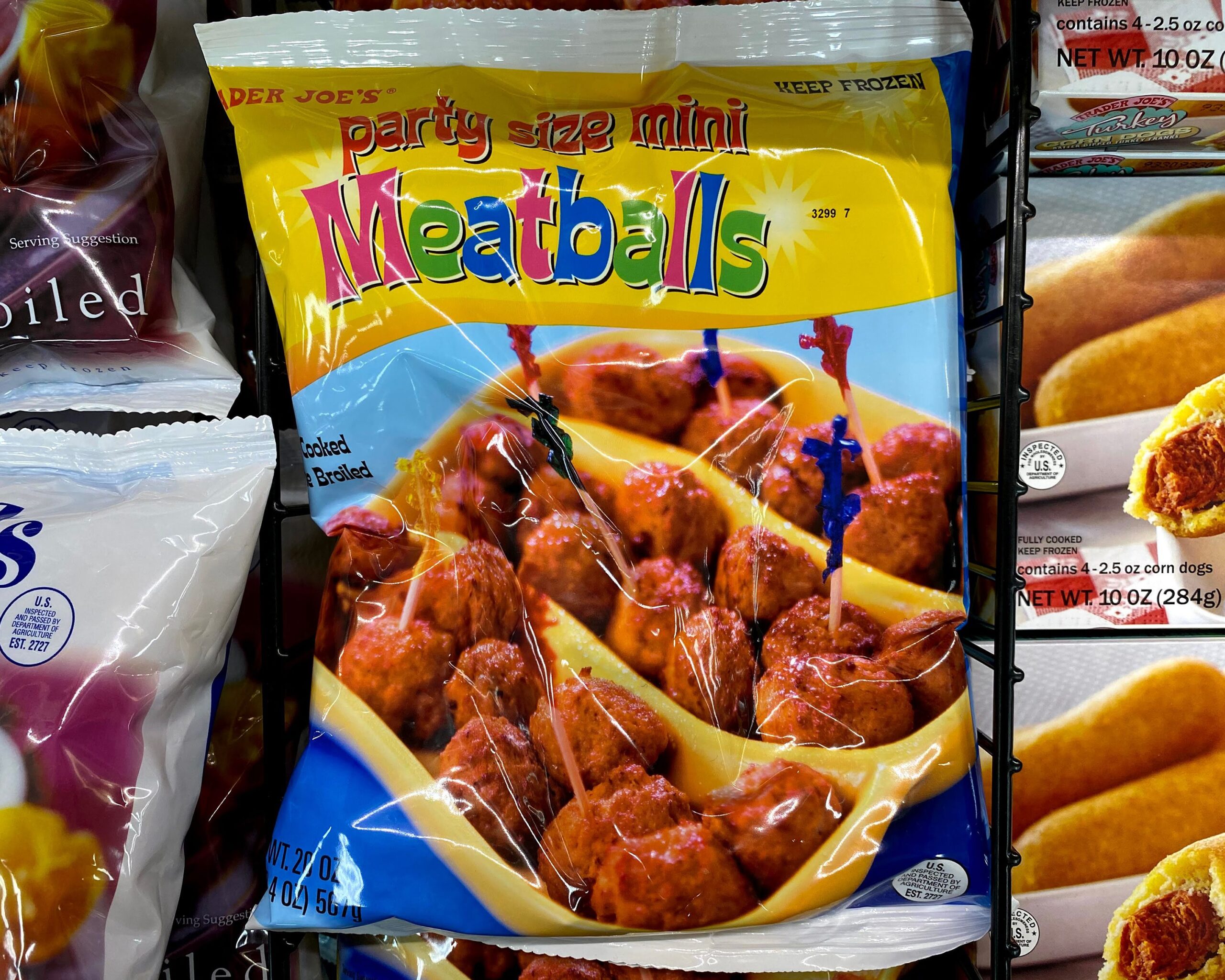 Pile of bags of Trader Joe's Party Size Mini Meatballs at a Trader Joe's, in a refrigerator, other foods in bags on both sides