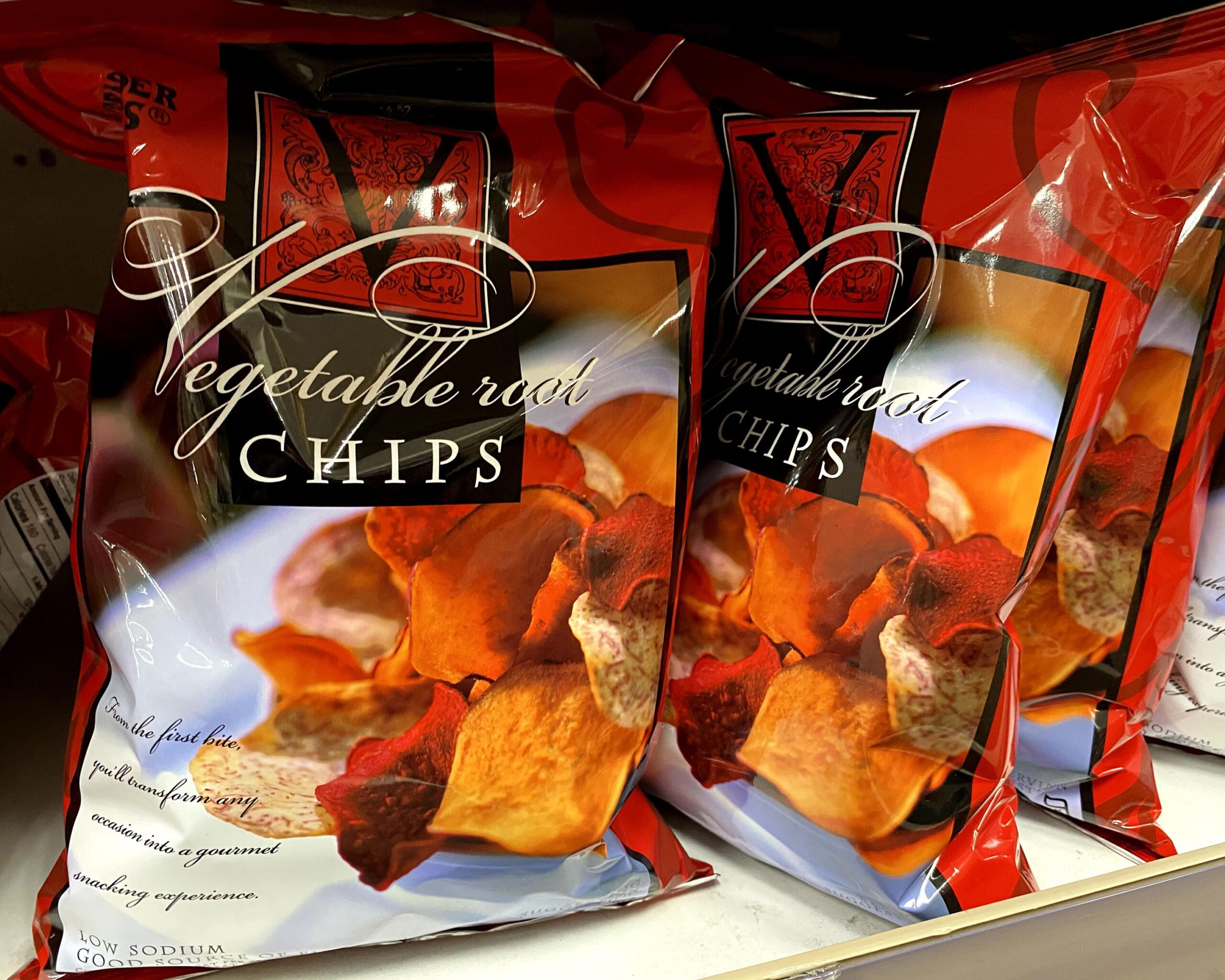 Many bags of Trader Joe's Vegetable Root Chips at a Trader Joe's, on a shelf