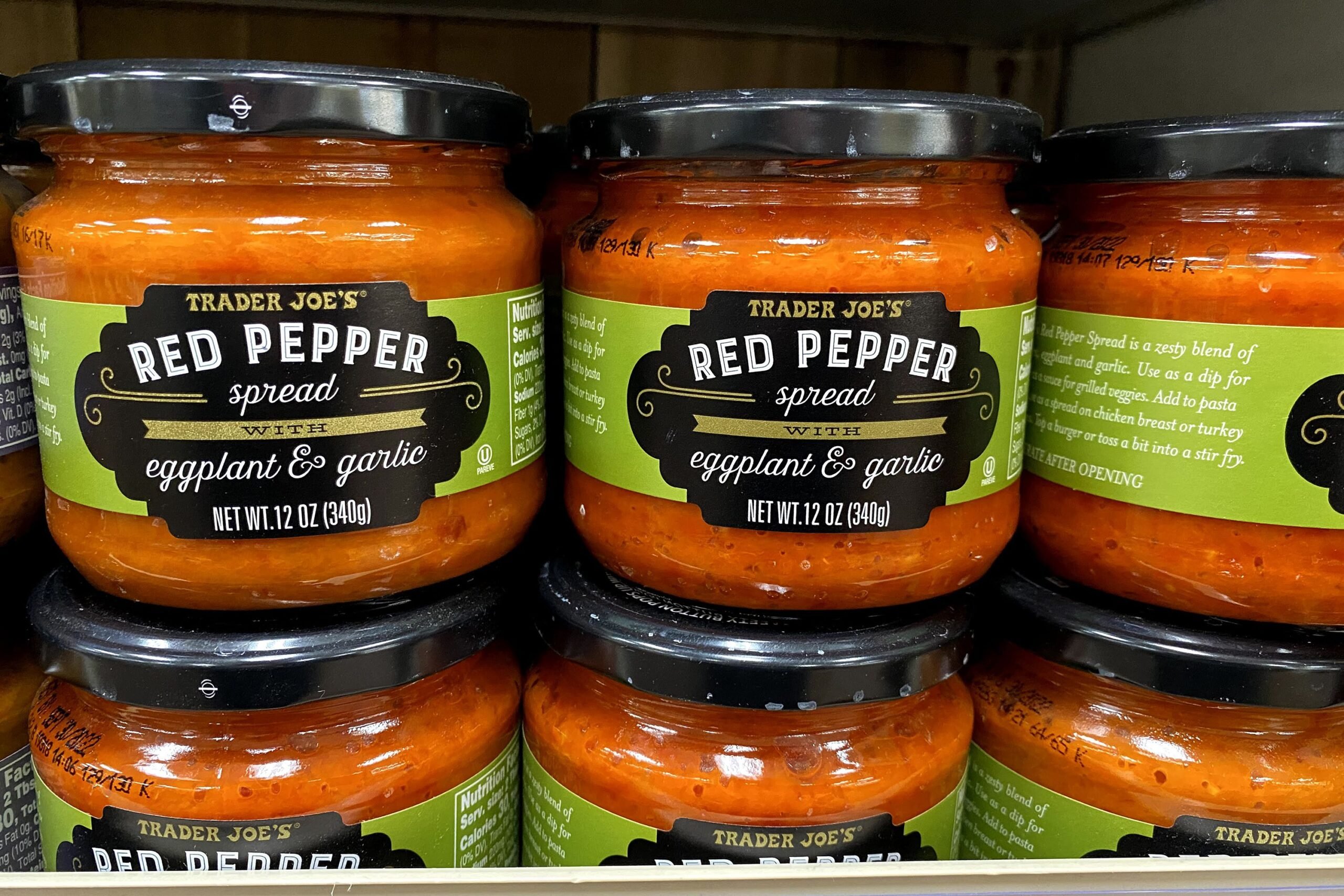 Three rows of jars of Trader Joe's Red Pepper Spread With Eggplant and Garlic at a Trader Joe's on a shelf, one jar on top of another