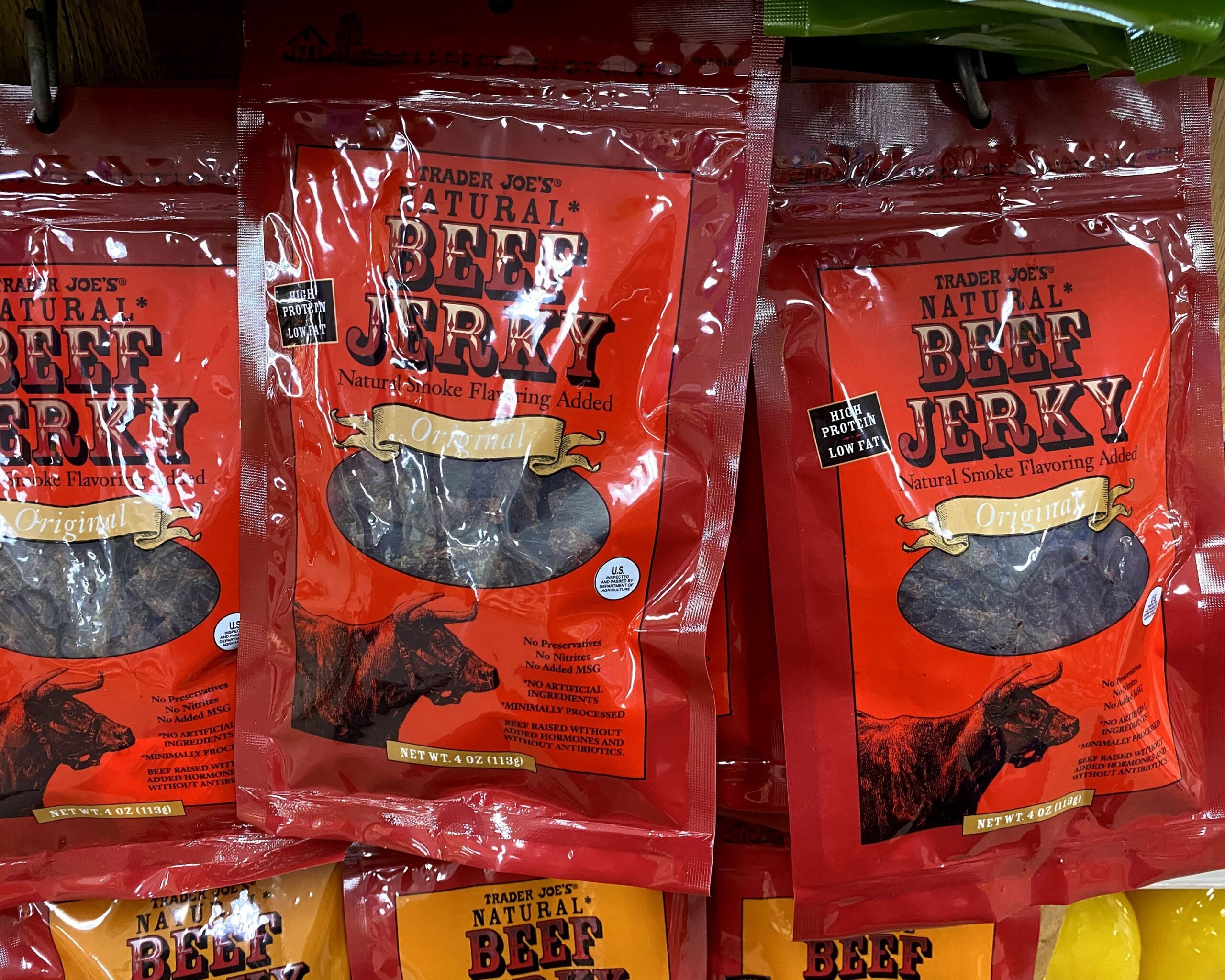 Several packages of Trader Joe's Beef Jerky at a Trader Joe's, hung in three rows, more kinds of beef jerky underneath them