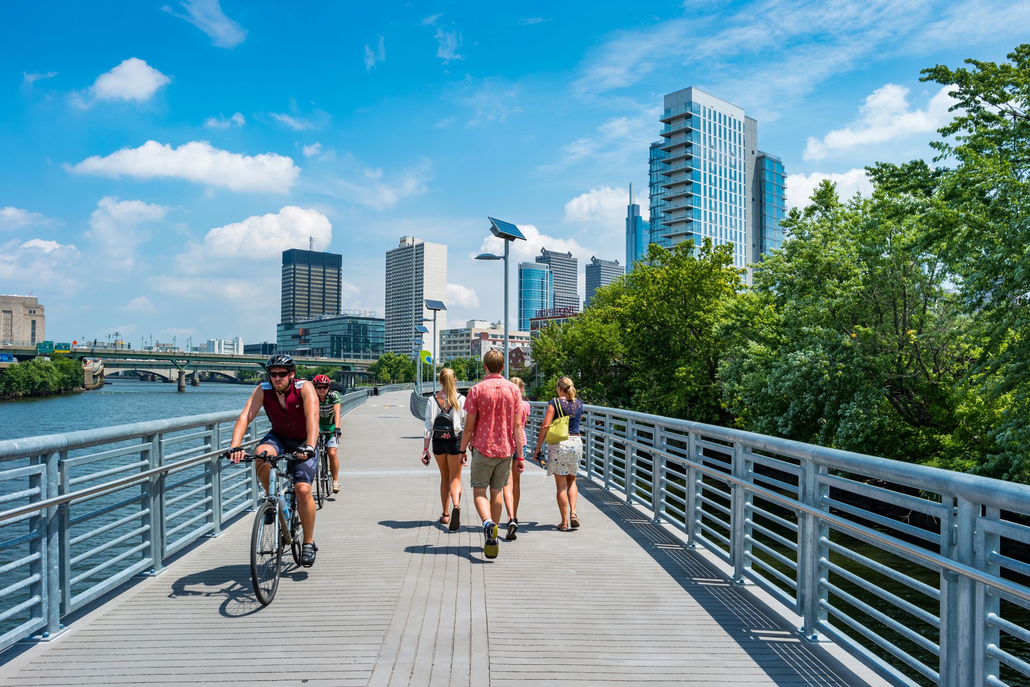 People bike and walk on the Schuylkill Banks Boardwalk in downtown Philadelphia, Pennsylvania, USA on a sunny summer day