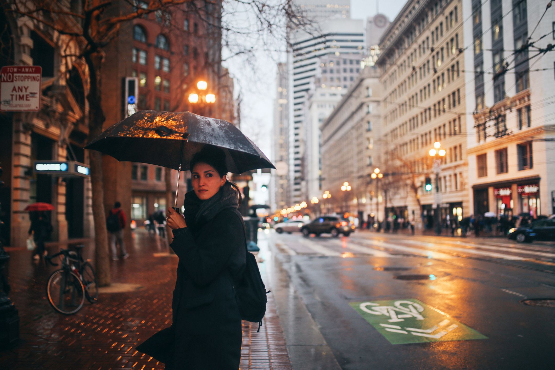 young woman standing with umbrella on rainy evening in San Francisco