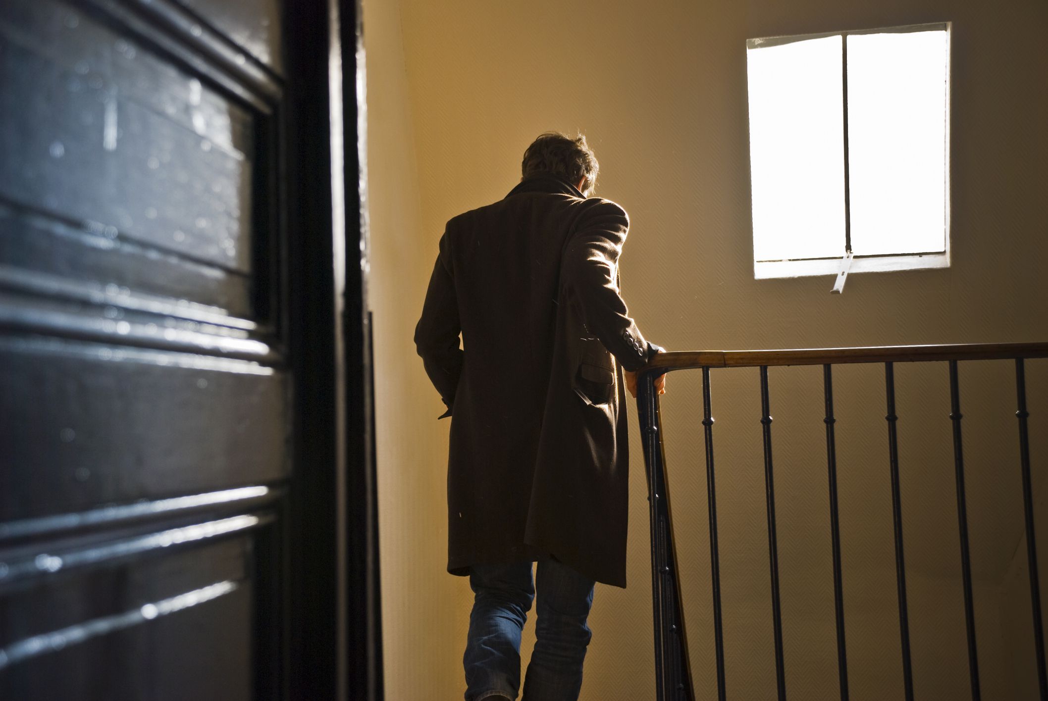 man leaving apartment, heading down staircase