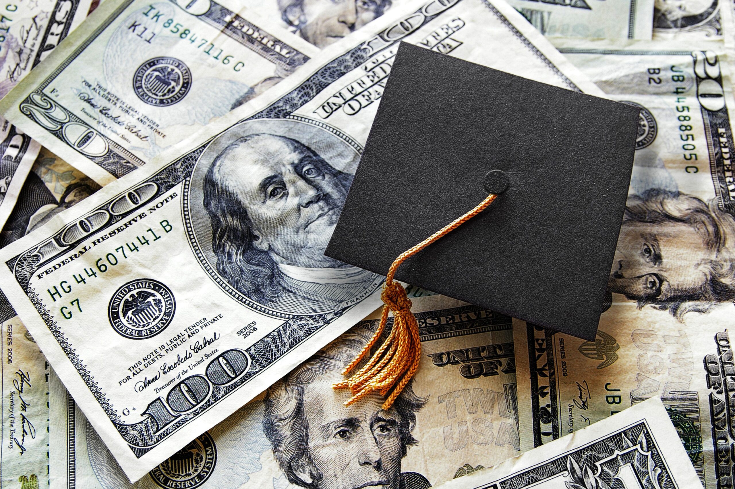 college graduation cap on a pile of money