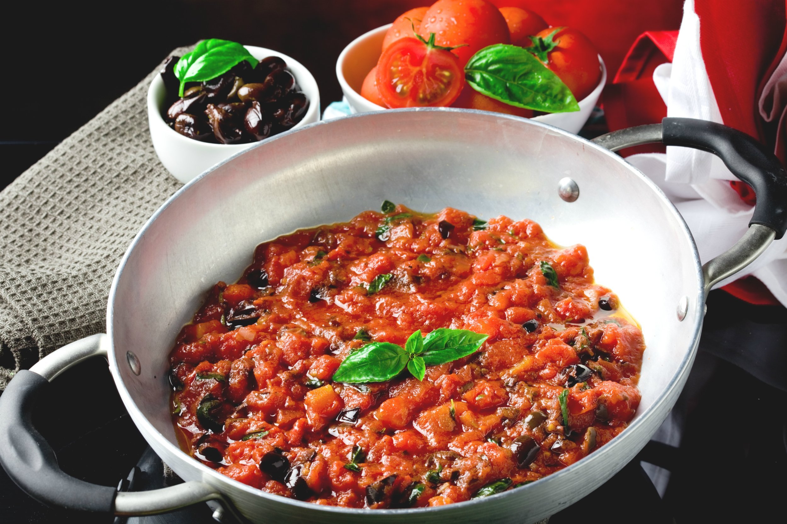 photo of fresh cooked tomato sauce with olives and basil