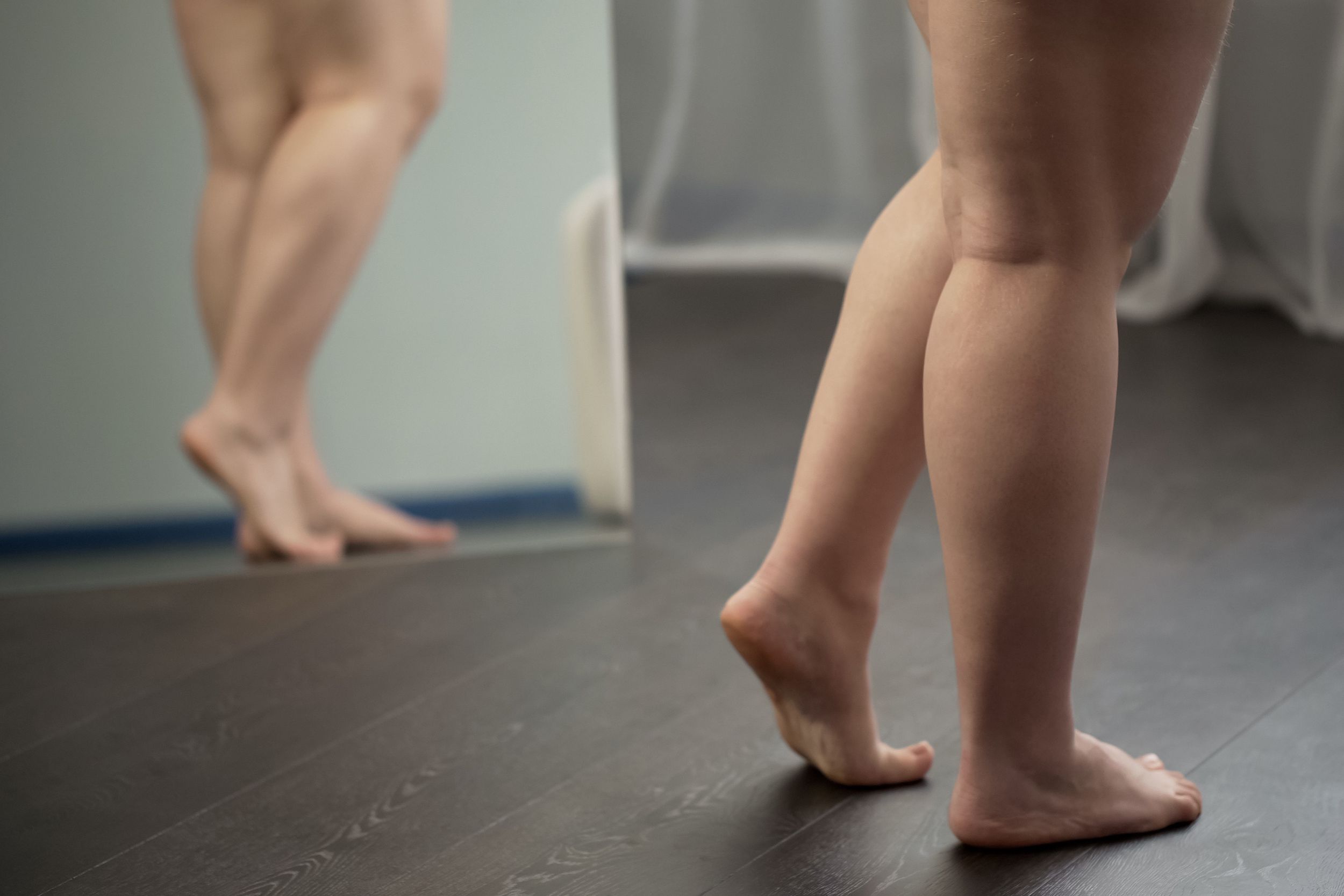 shot of woman's legs and feet while she is looking at herself in mirror