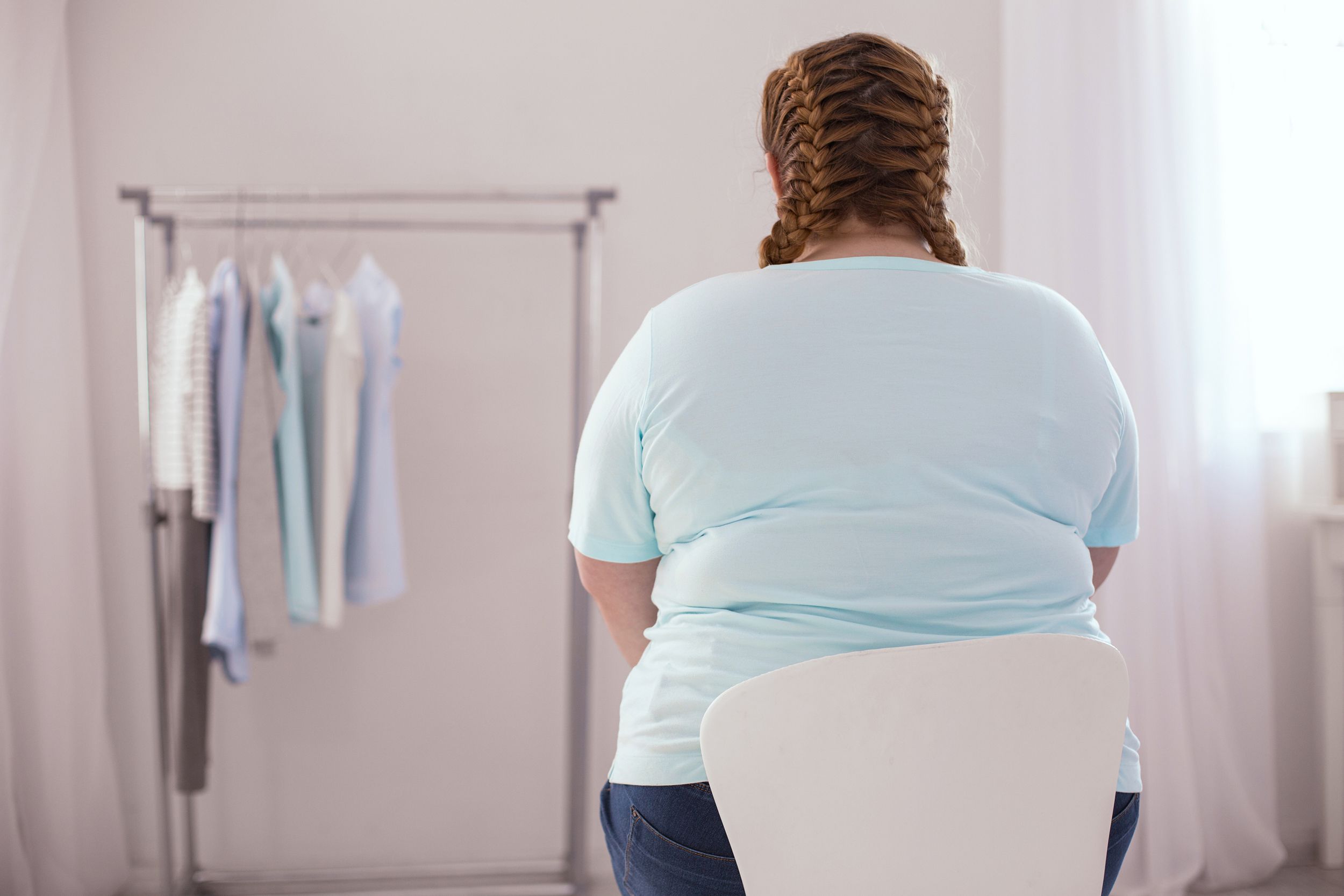 overweight young woman sitting on the chair while thinking about new clothes
