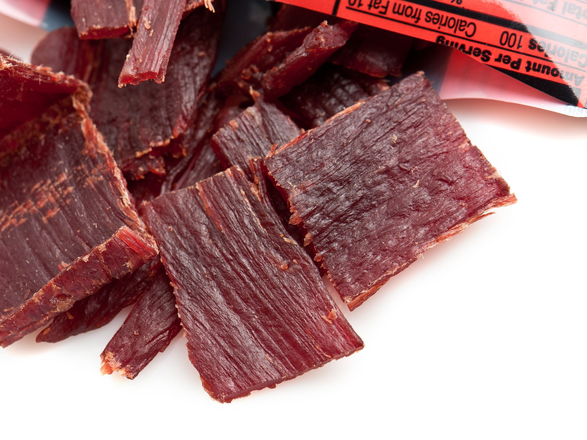 Beef jerky coming out of the bag on white background