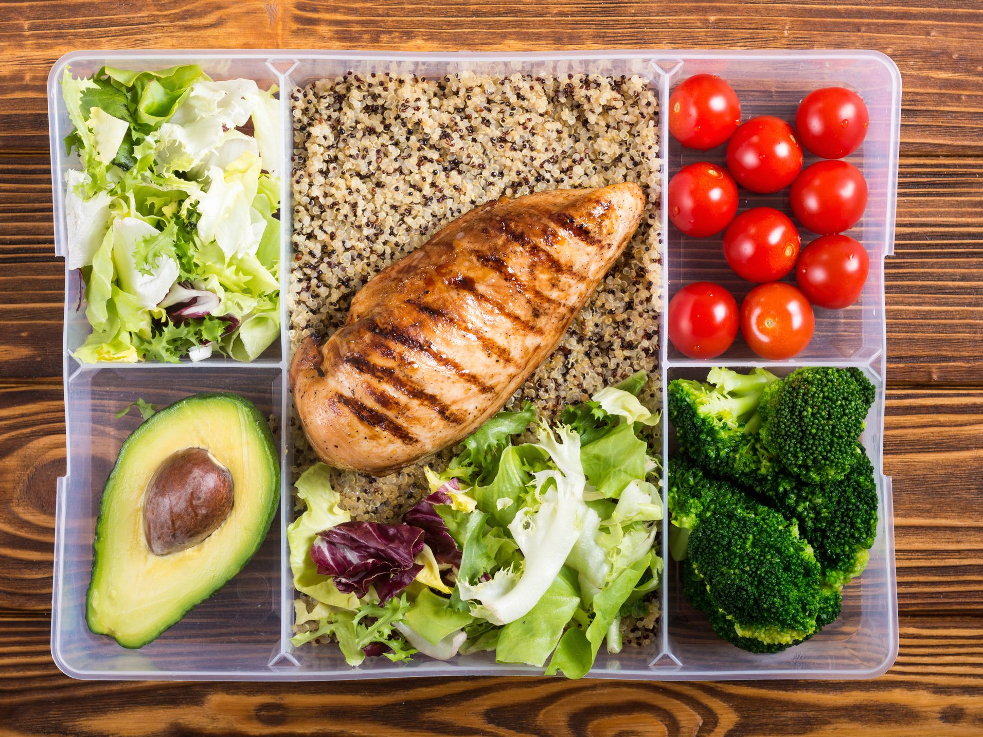 Food plastic container with lunch. Qinoa chicken tomatoes broccoli avocado and salad